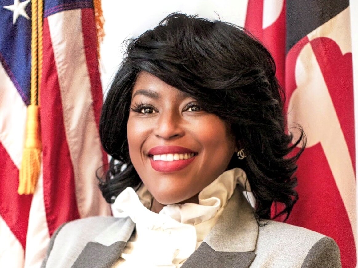 Erica Griswold poses for a portrait in front of a Maryland state flag.