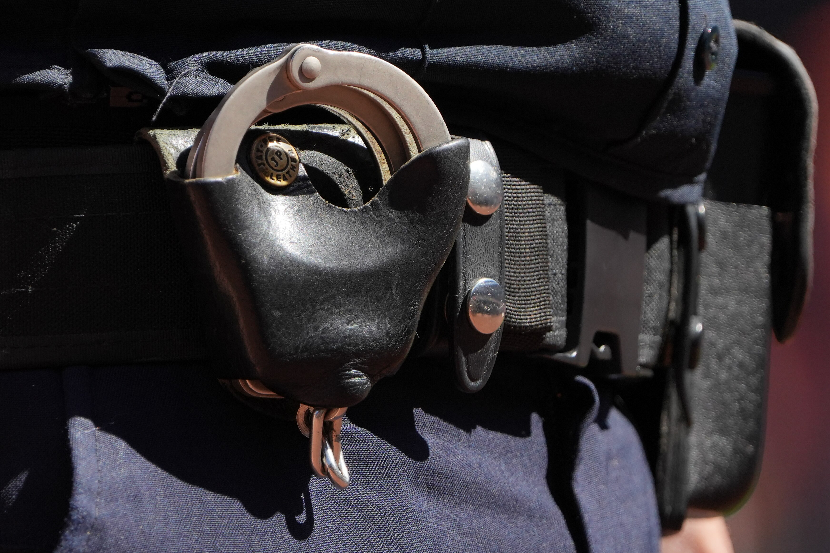 A Baltimore Police detective’s handcuffs are secured on his belt as he observes a crowd in Baltimore in April 2023.