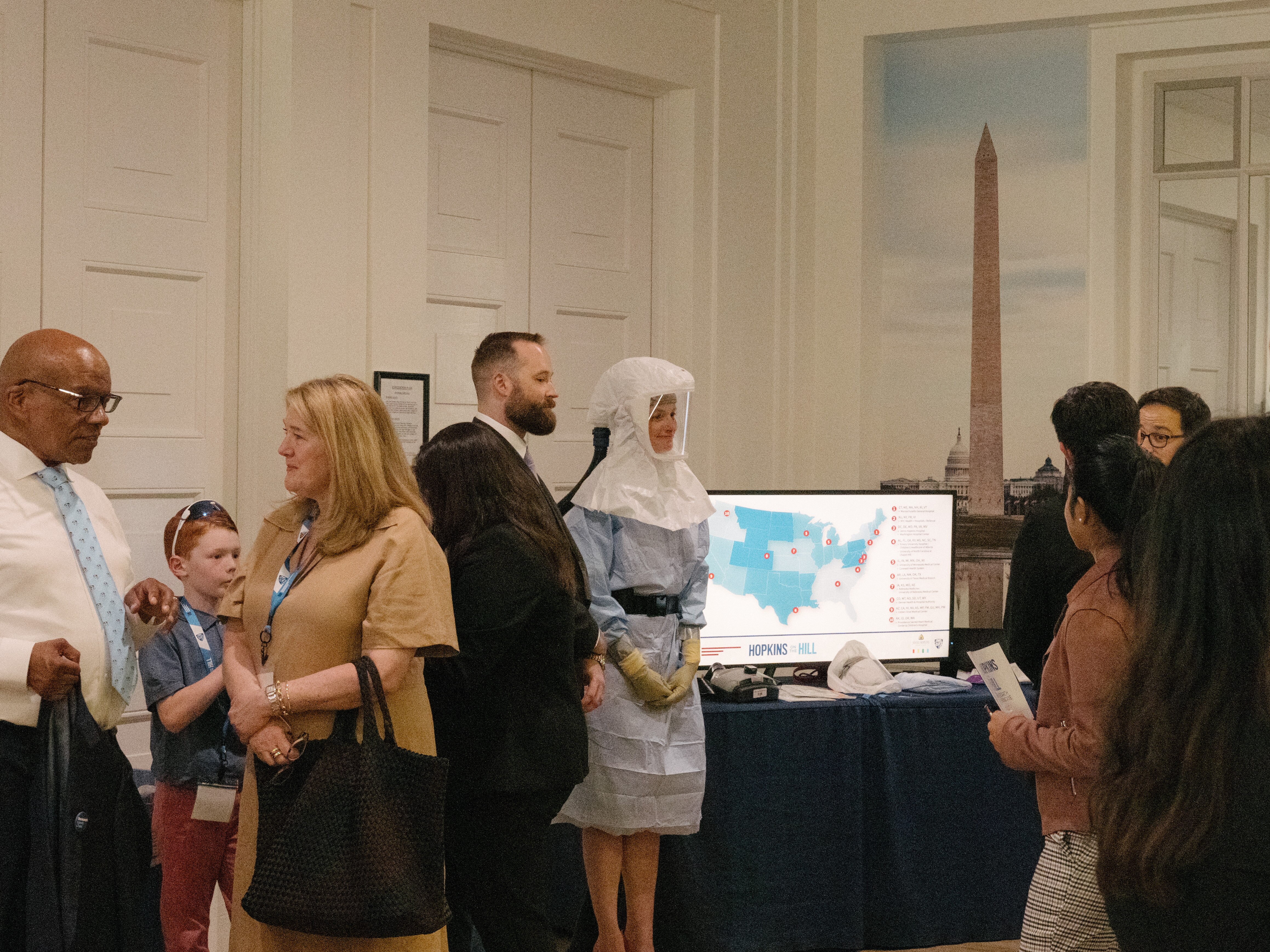 Carrie Billman, wearing a protective hood, joins colleagues to talk about their research into safeguarding against lethal pathogens at the Hopkins on the Hill research showcase in the Rayburn House Office Building in Washington, D.C., on June 12, 2025.