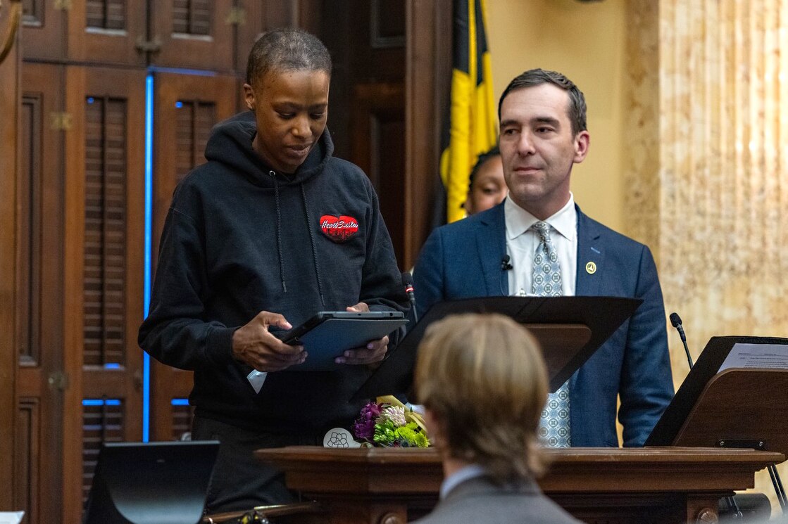 Zeke Cohen, right, stands with Joni Holifield during a Baltimore City Council meeting where Holifield was honored for her work with the city.