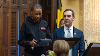 Zeke Cohen, right, stands with Joni Holifield during a Baltimore City Council meeting where Holifield was honored for her work with the city.