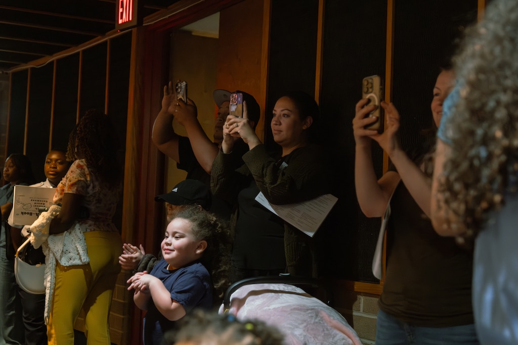 Attendees at the back of the auditorium film during the award ceremony of the Prince George's County Write-A-Book contest, held at Eleanor Roosevelt High School.