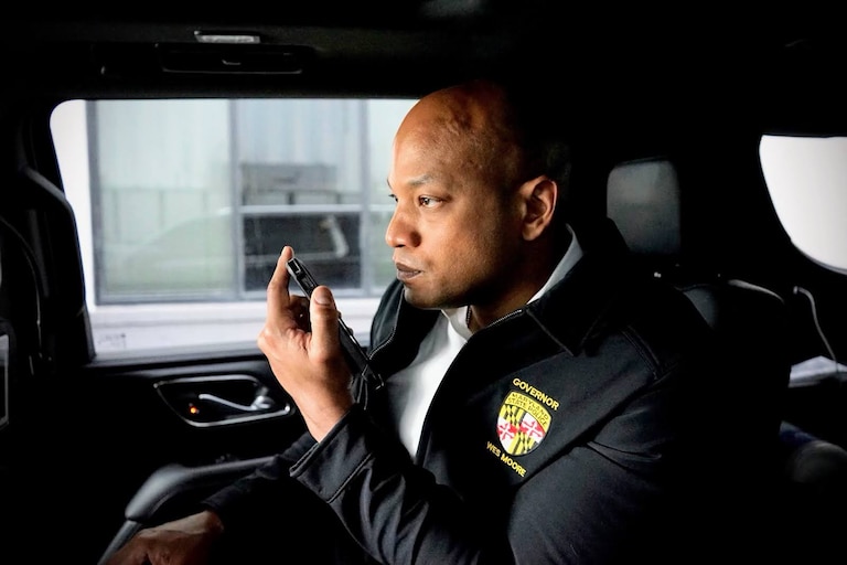 Gov. Wes Moore using his phone from the back of the official Chevy Suburban.