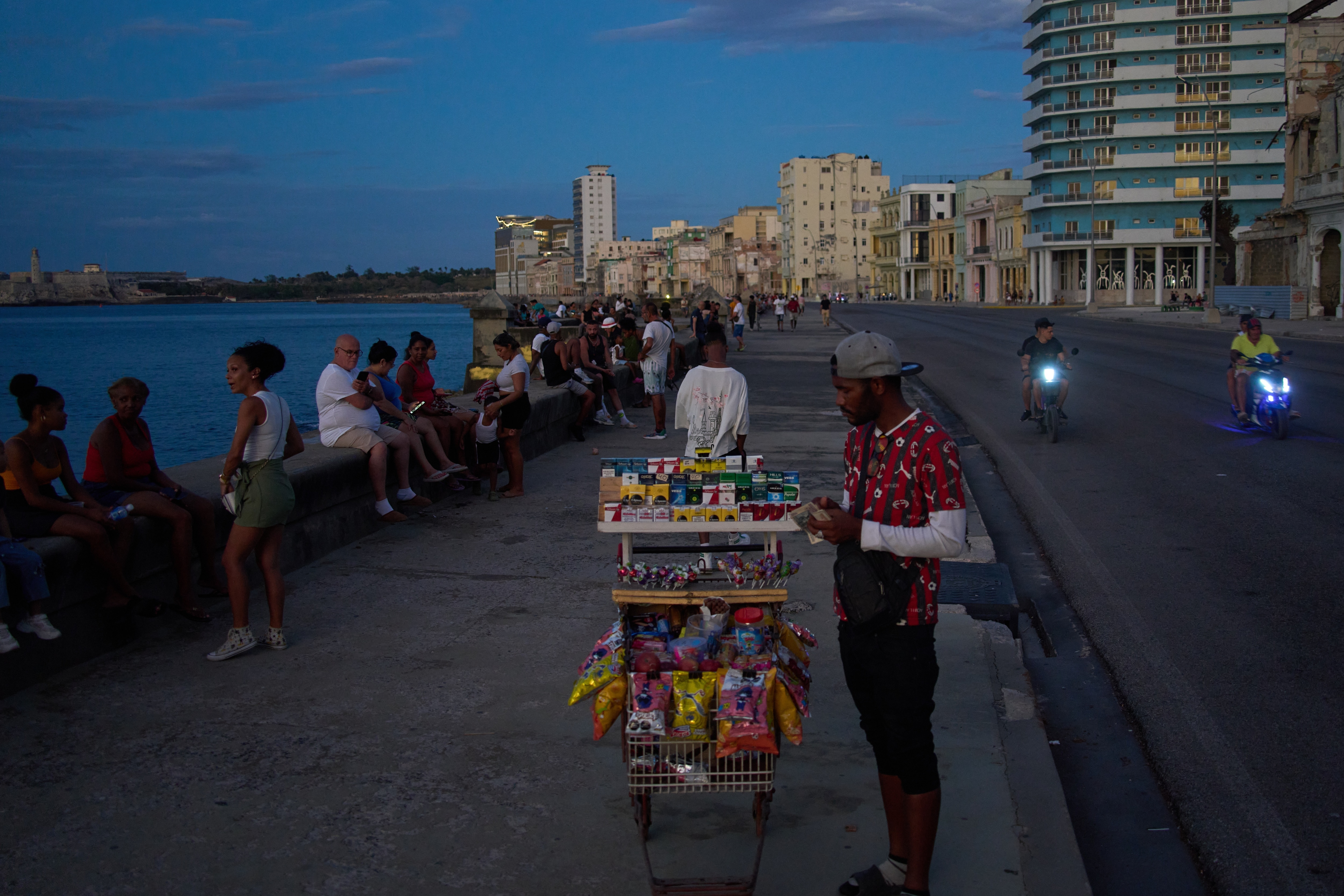 A street vendor waits for customers on the Malecón during a blackout in Havana, Monday, March 16, 2026.