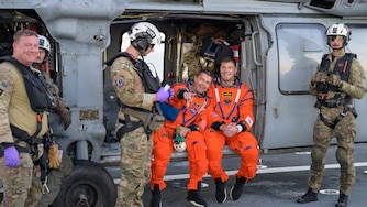NASA astronaut Reid Wiseman, Artemis II commander, left, and CSA (Canadian Space Agency) astronaut Jeremy Hansen, Artemis II mission specialist, are seen sitting on a Navy MH-60 Seahawk from Helicopter Sea Combat Squadron (HSC) 23 on the flight deck of USS John P. Murtha after they and fellow crewmates NASA astronaut Christina Koch, Artemis II mission specialist, and NASA astronaut Victor Glover, Artemis II pilot, were extracted from their Orion spacecraft after splashdown, Friday, April 10, 2026, in the Pacific Ocean off the coast of California. NASA’s Artemis II mission took the quartet on a nearly 10-day journey around the Moon and back to Earth. Following a splashdown at 5:07 p.m. PDT (8:07 p.m. EDT), NASA, U.S. Navy, and U.S. Air Force teams are working to bring the Orion spacecraft aboard the recovery ship.