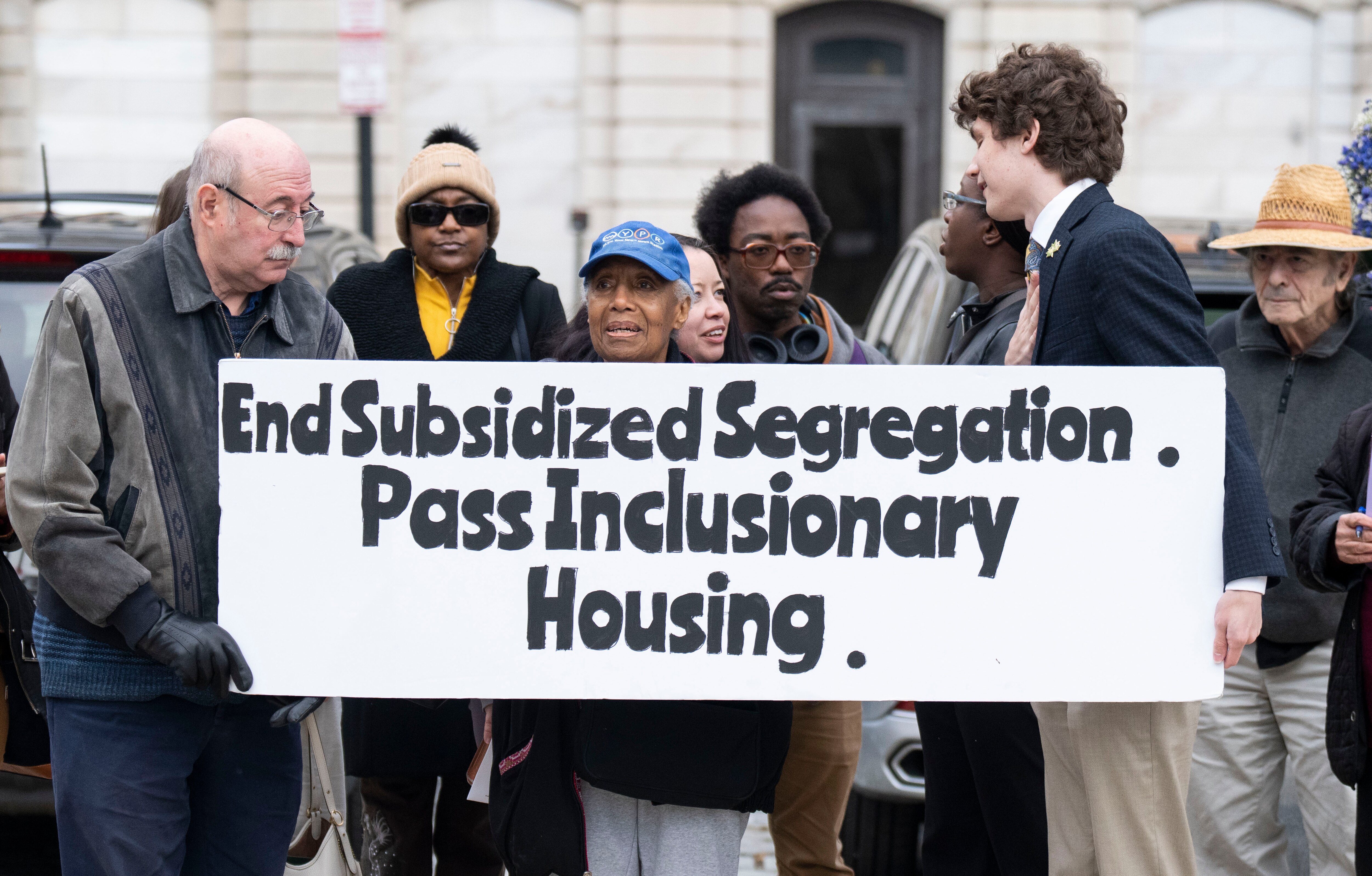 Demonstrators hold a sign during a rally outside City Hall during a rally for the inclusionary housing bills in Baltimore on Monday, Nov. 20, 2023.