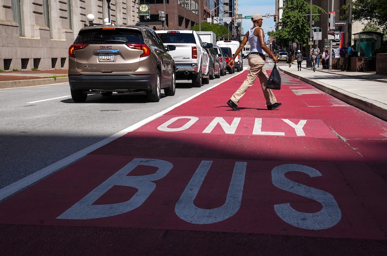 A man walks across a Bus Only lane outside Charles Center Station on 8/11/22.