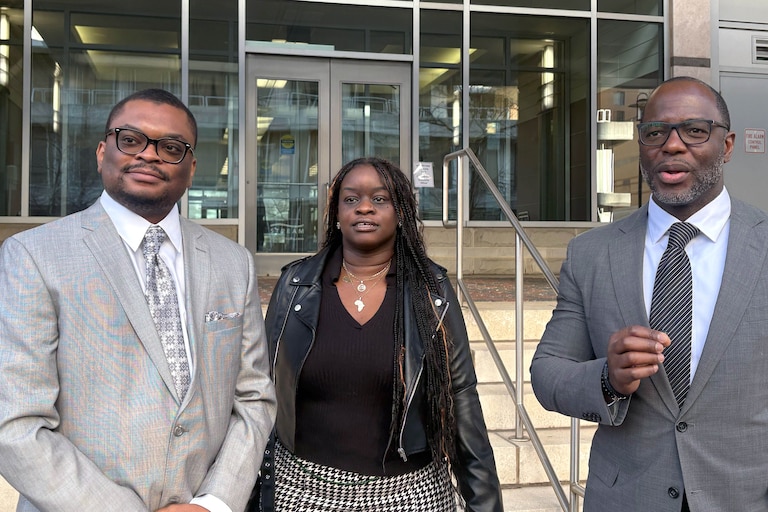 MARCH 13, 2026 - Ludovic Mbock's friend Nikhil Delahaye, Mbock's sister, Diane Sohna and Mbock's attorney, Edward Neufville outside immigration court in Hyattsville.