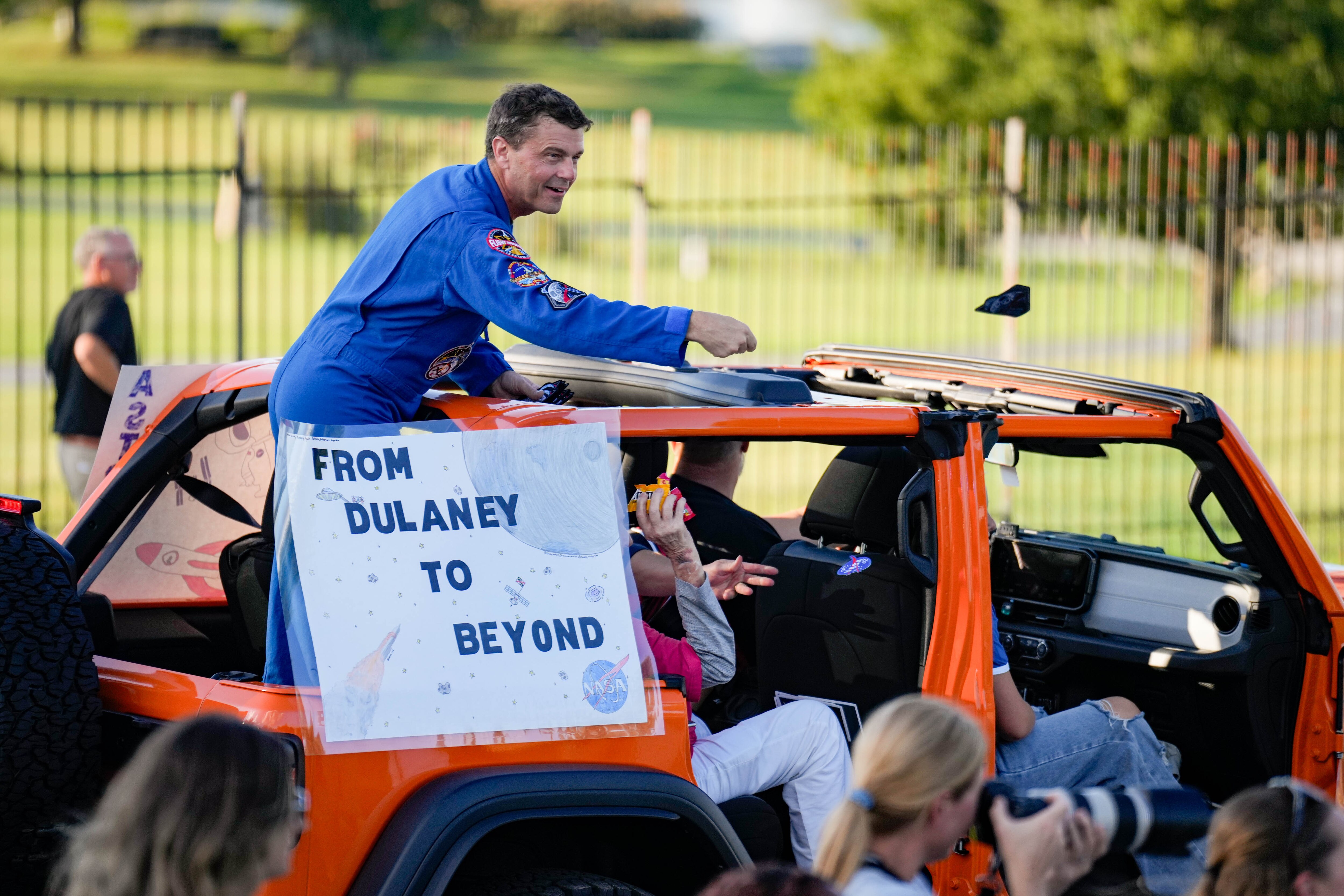 Astronaut Reid Wiseman tosses out NASA patches to onlookers as he passes by in the Dulaney High School homecoming parade on Friday.