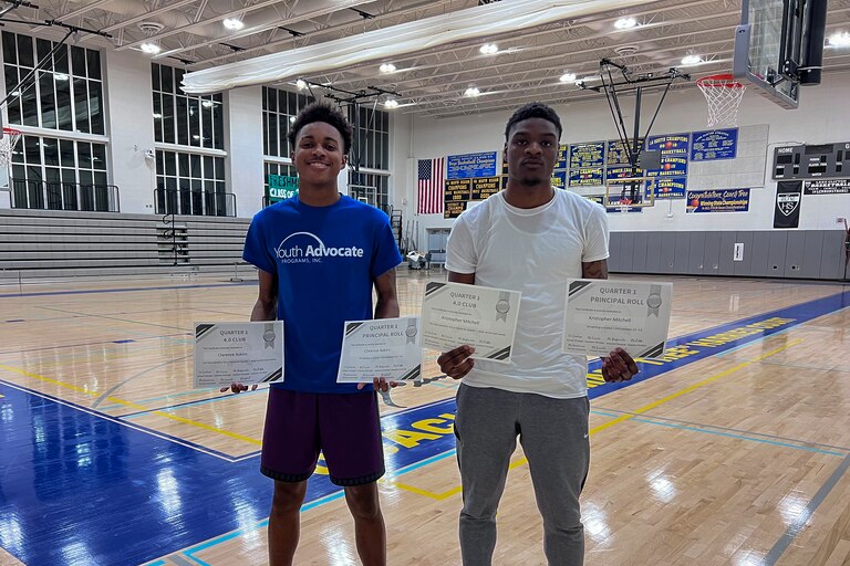 Clarence “Ray” Askins (left), 17, and Kristopher Mitchell (right), 17, show off their 4.0 GPA certificates in the gym of the REACH! Partnership school.