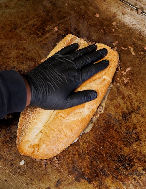 Armand Miles, owner of Dimples Bar & Grill in Locust Point, prepares a cheesesteak.