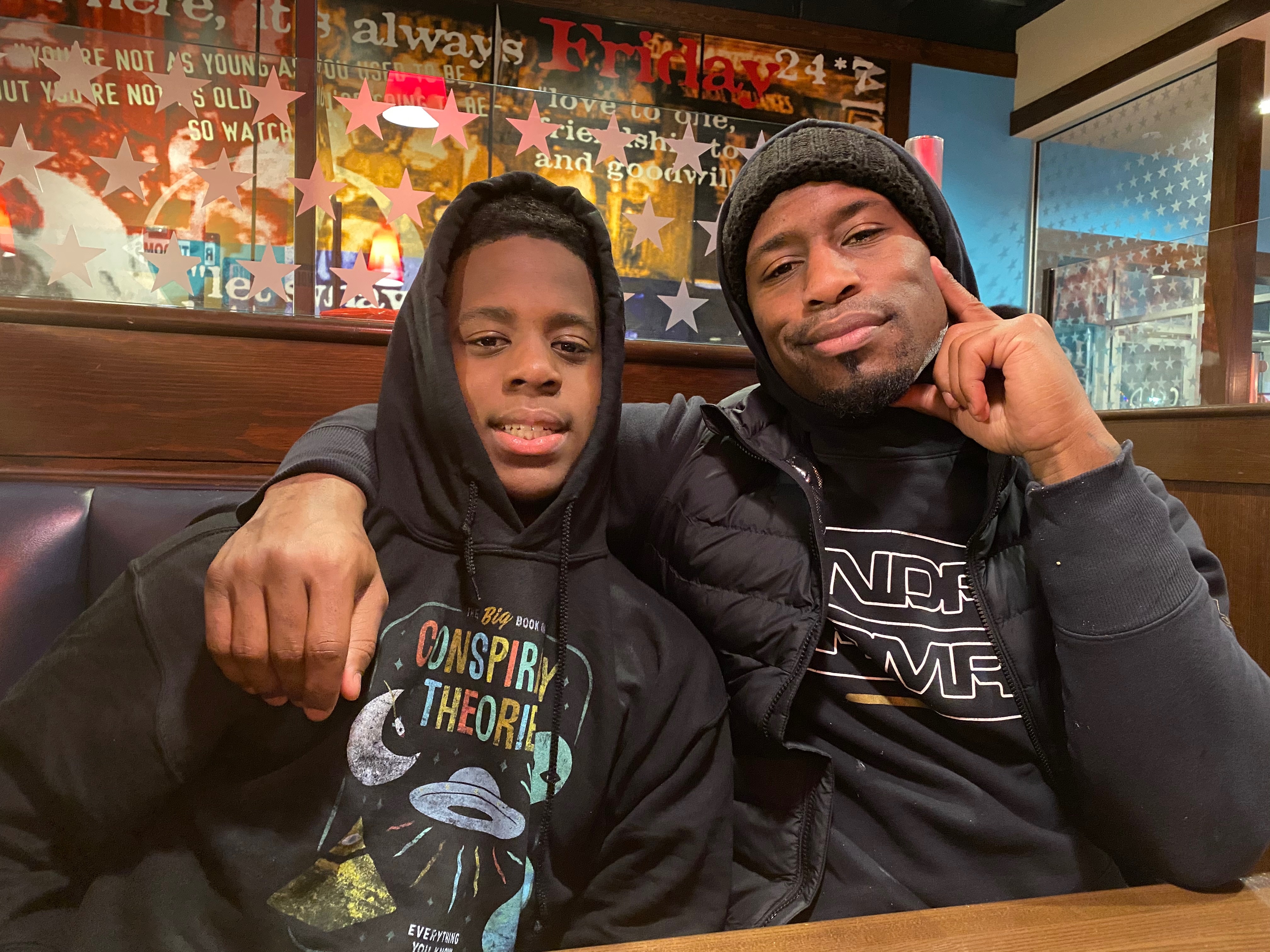 Jianni Davis, left, and Vernon Davis sit in a restaurant with Vernon's arm draped over his son.