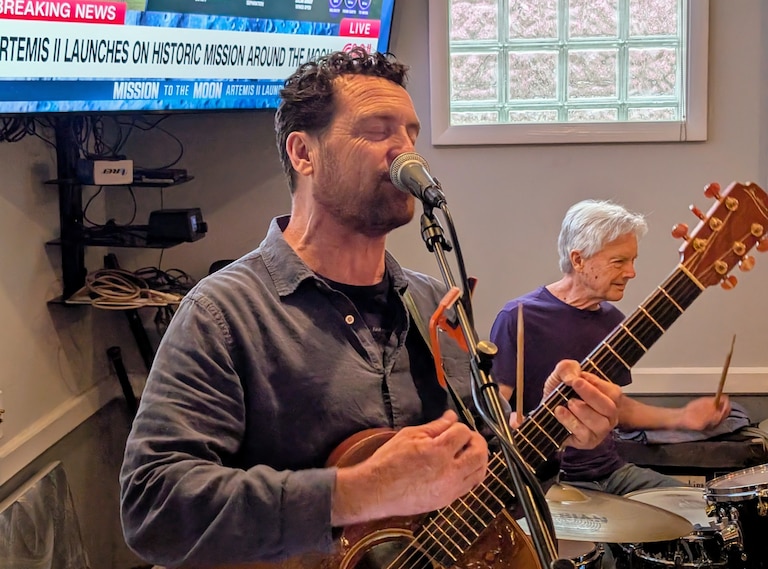 Annapolis singer Dan Haas sings "Fly Me to the Moon" as the launch of Aretemis II is carried on a TV screen behind him on April 1, 2026 in Annapolis.