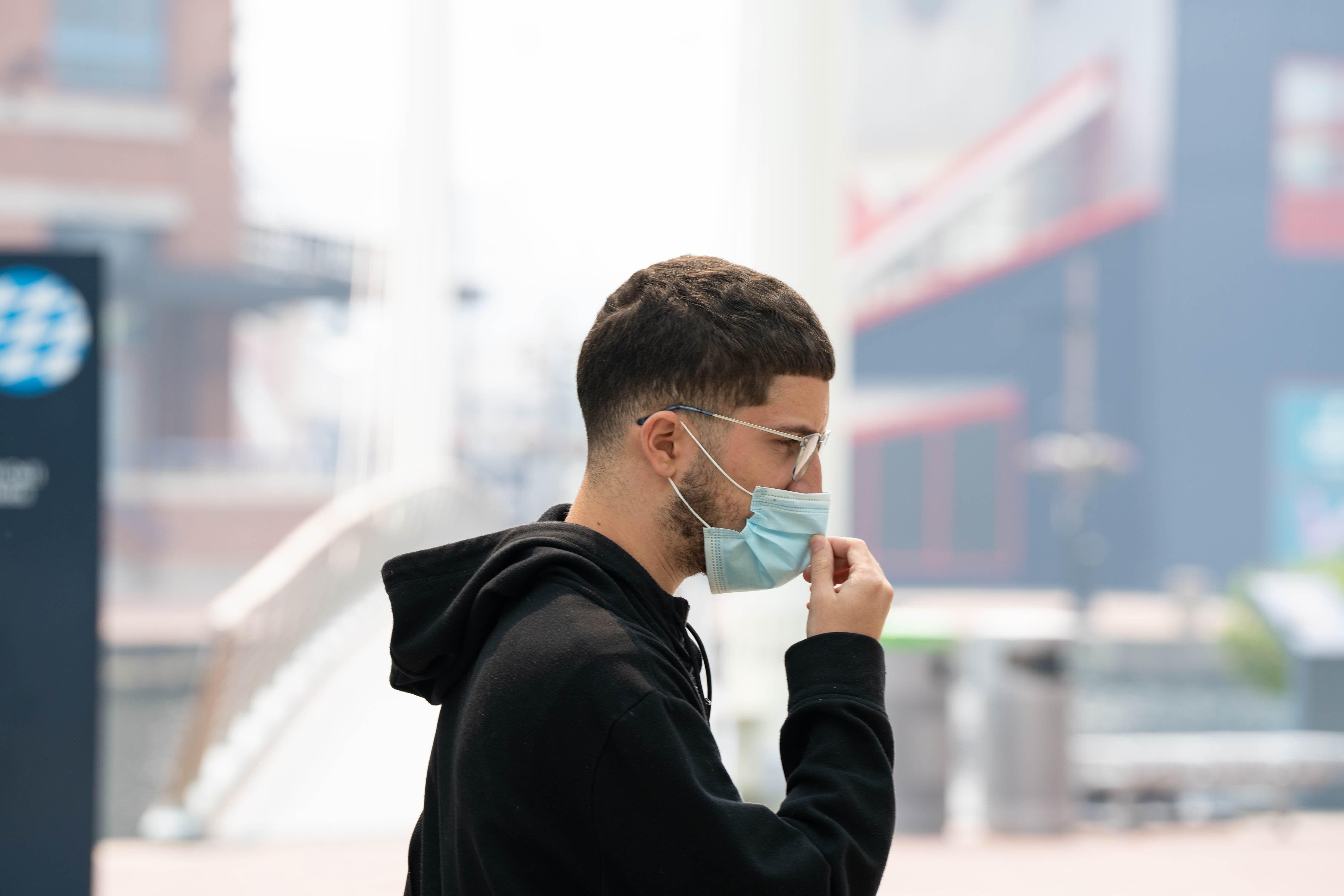 A man walks in the Inner Harbor as Baltimore is blanketed in dangerous levels of smoke from Canadian wildfires on Thursday, June 8, 2023.