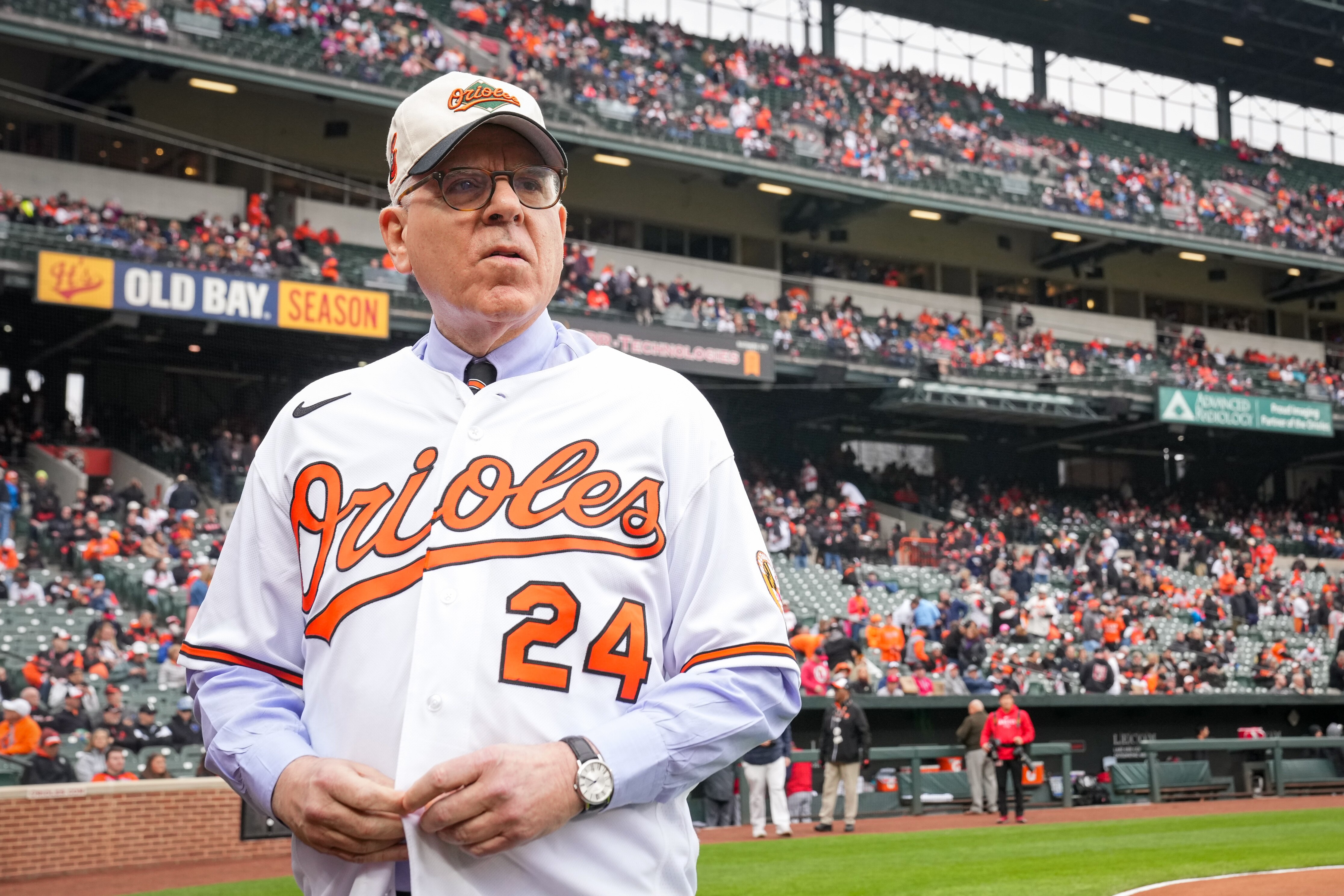 Orioles owner David Rubenstein adjusts his jersey on the field at Camden Yards on opening day.
