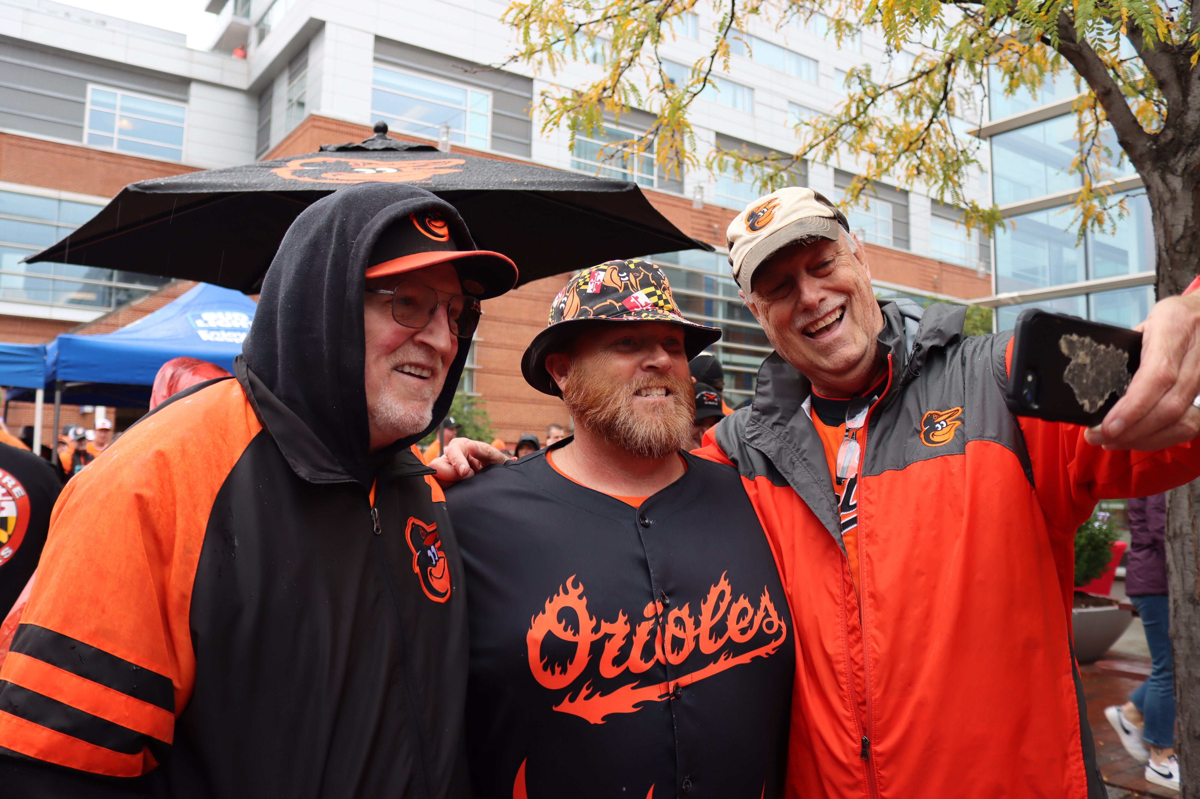 Orioles fan Merrill Heim (center), also known as "Fired Up Guy," poses for a selfie at a tailgate outside Camden Yards on Oct. 7, 2023.