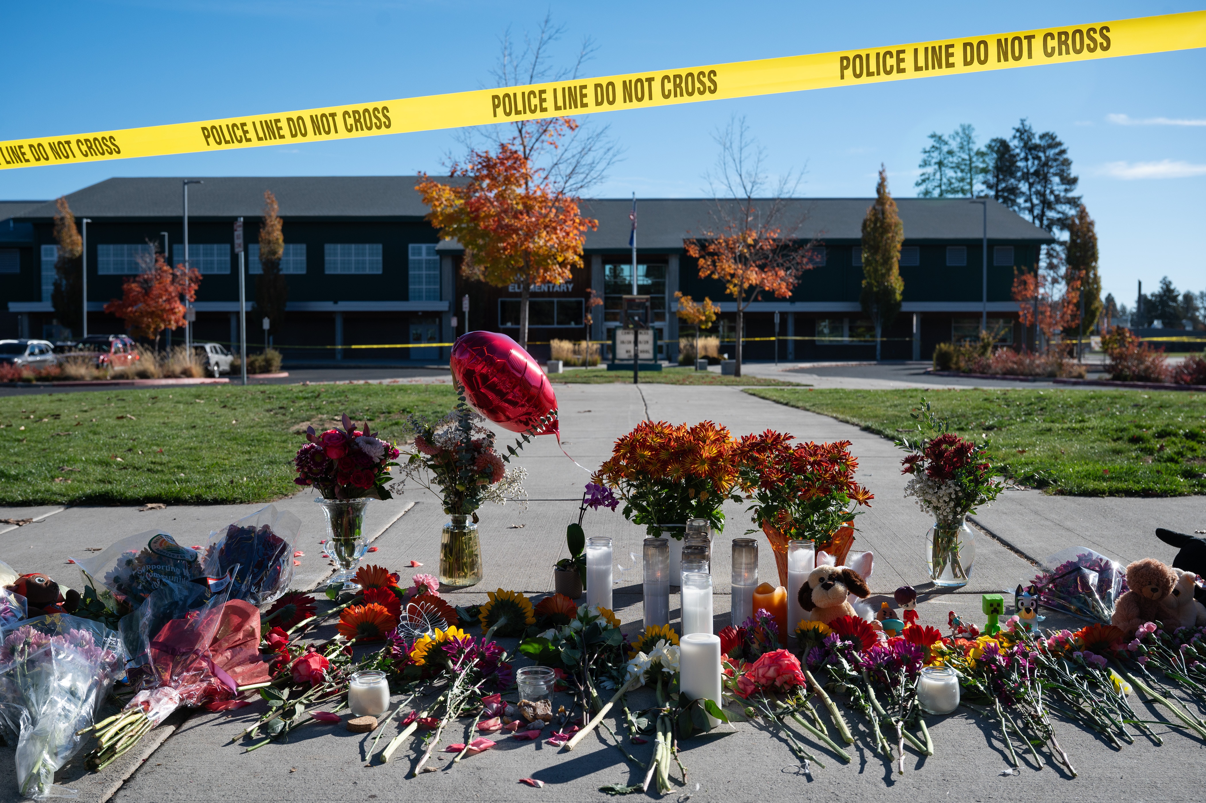 Flowers and candles are seen at a makeshift memorial outside Silver Rail Elementary in Bend, Ore., Friday, Oct. 16, 2026, a day after a deadly shooting.
