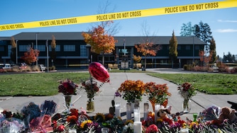 Flowers and candles are seen at a makeshift memorial outside Silver Rail Elementary in Bend, Ore., Friday, Oct. 16, 2026, a day after a deadly shooting.