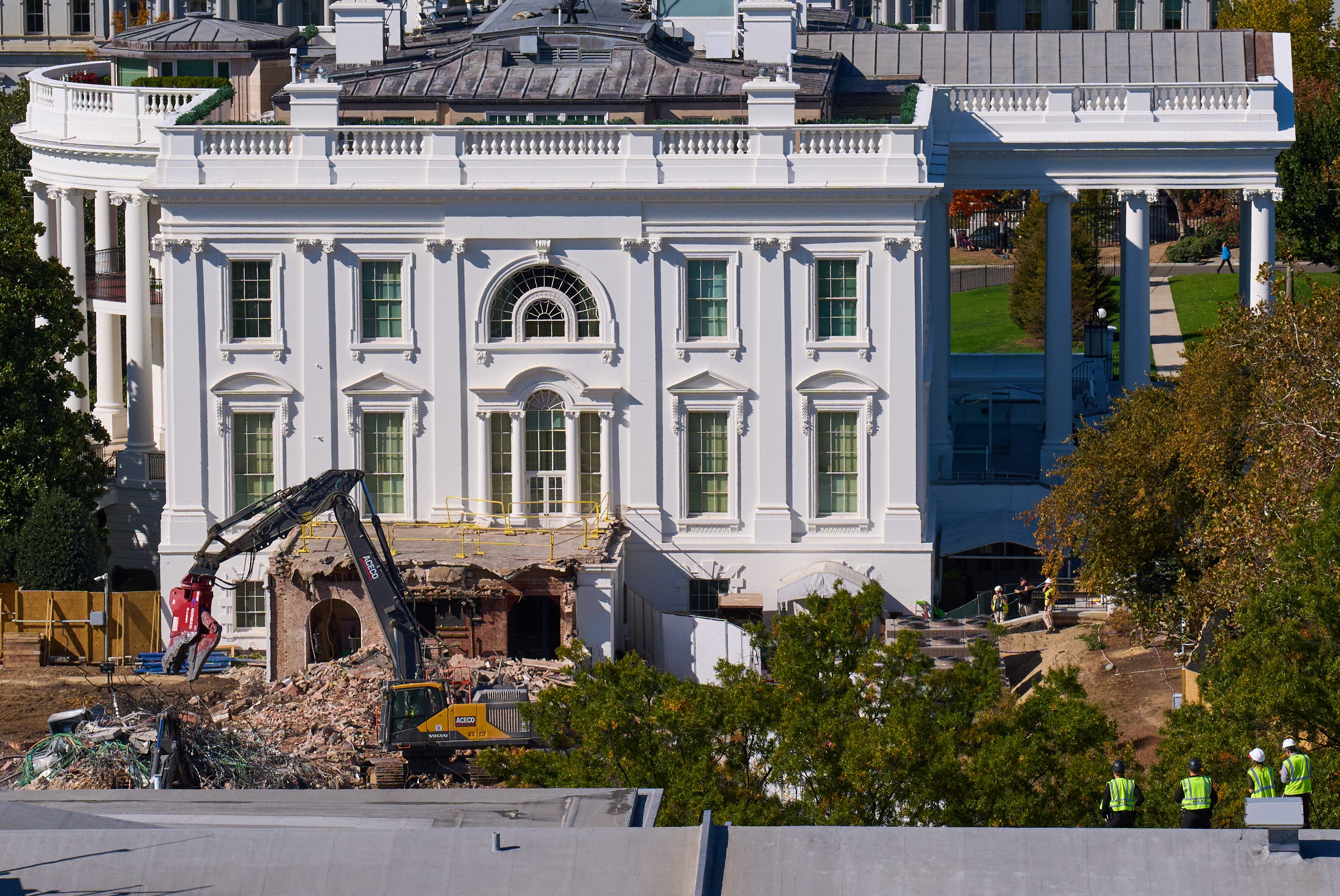 Construction workers, bottom right, atop the U.S. Treasury, watch as work continues on a largely demolished part of the East Wing of the White House, Thursday, Oct. 23, 2025, in Washington, before construction of a new ballroom.
