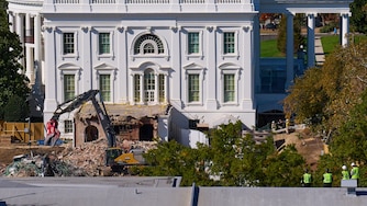 Construction workers, bottom right, atop the U.S. Treasury, watch as work continues on a largely demolished part of the East Wing of the White House, Thursday, Oct. 23, 2025, in Washington, before construction of a new ballroom.