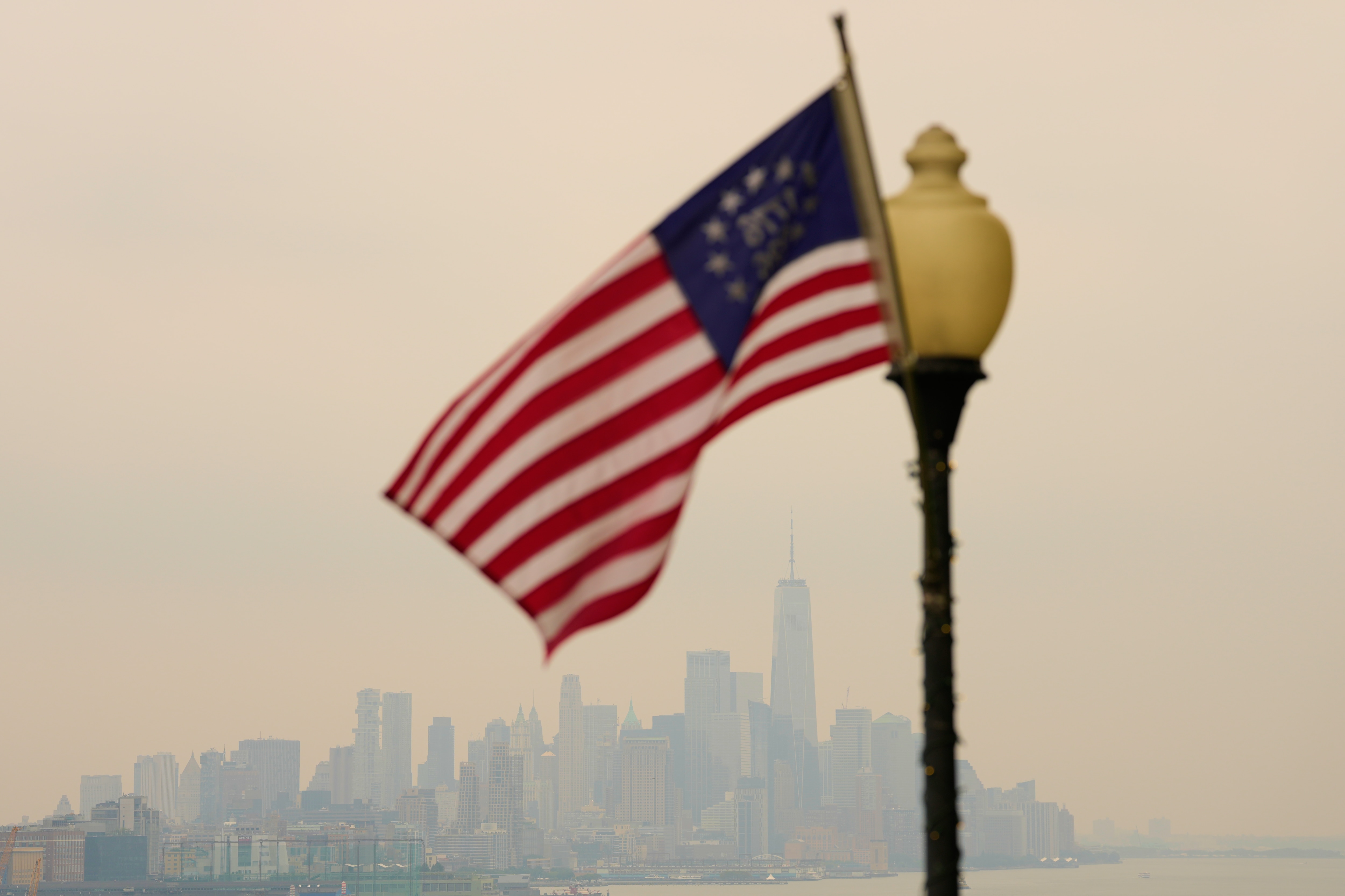 The New York City skyline is shrouded in smoke as a flag flies in a park in Weehawken, N.J., Thursday, July 16, 2026. (AP Photo/Seth Wenig)