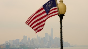 The New York City skyline is shrouded in smoke as a flag flies in a park in Weehawken, N.J., Thursday, July 16, 2026. (AP Photo/Seth Wenig)