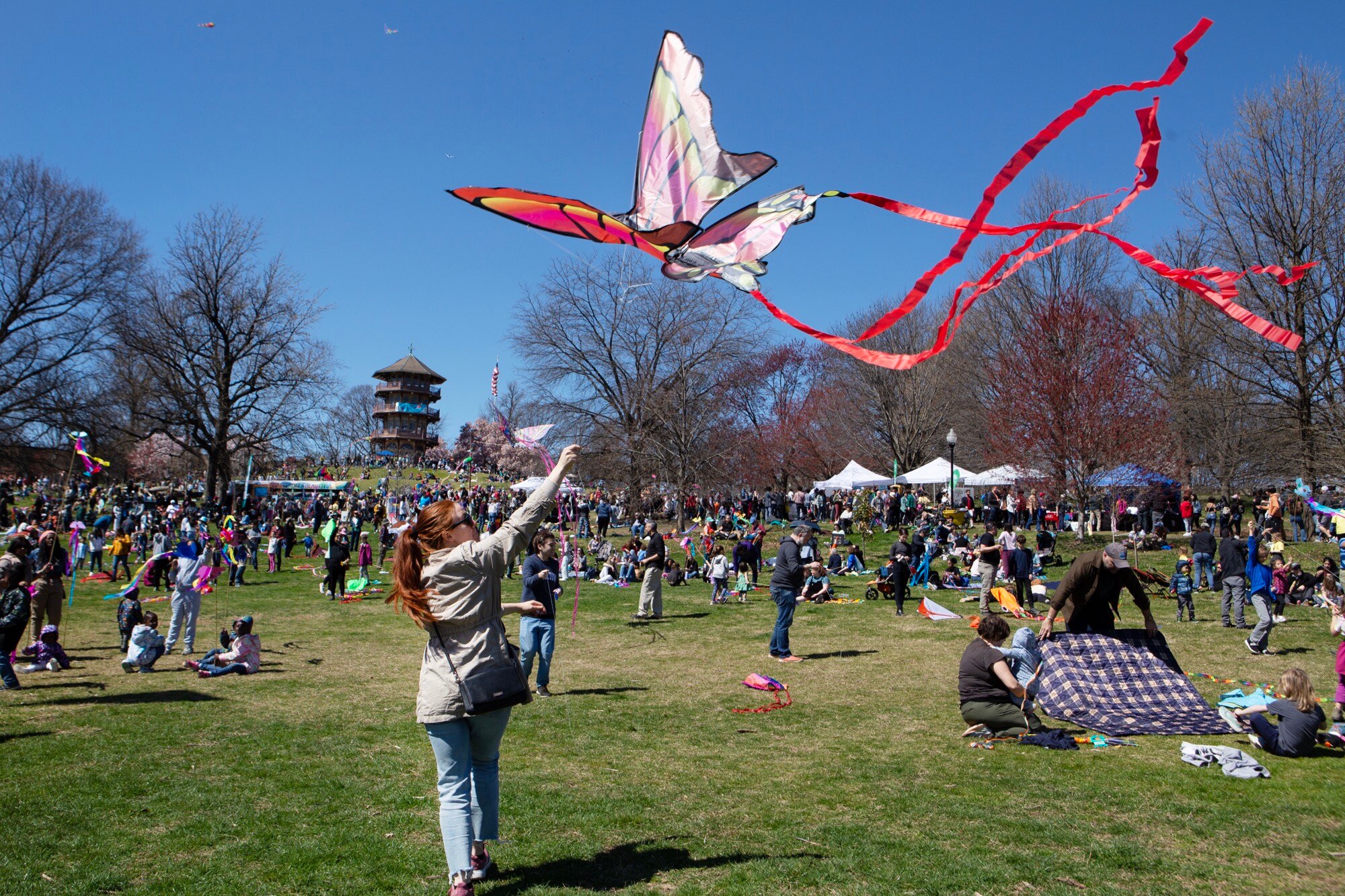 People enjoy a nice day by flying kites at Patterson Park during the Kite Festival on March 26, 2023. (Julia Reihs for The Baltimore Banner)