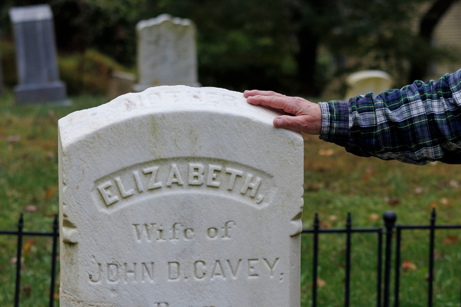 Ann Garvey rests a hand on a gravestone at the Oella Cemetery in Catonsville.