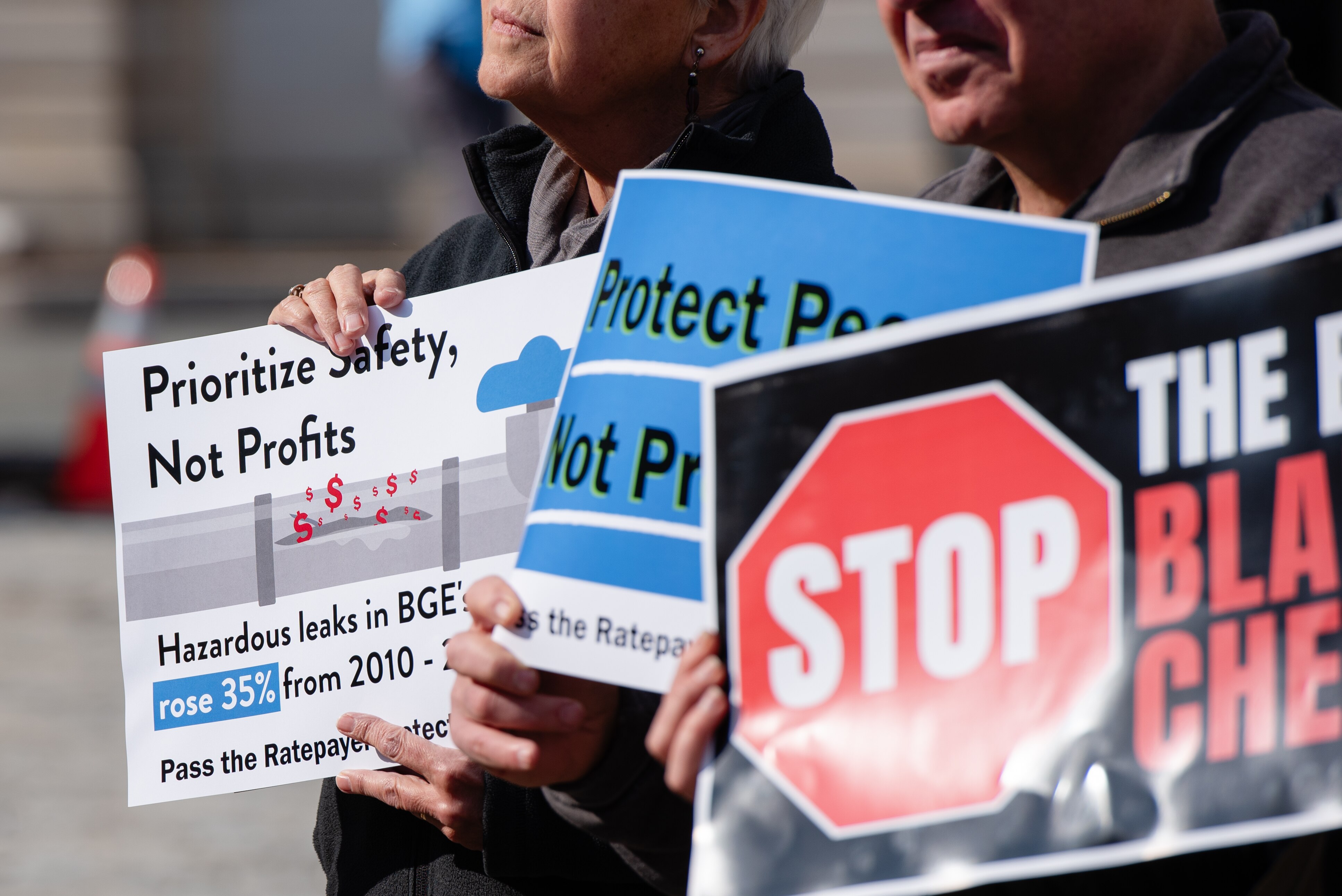 Supporters of legislation aimed at lower heating costs and improving public safety hold up signs during a press conference held outside of Baltimore City Hall in February.