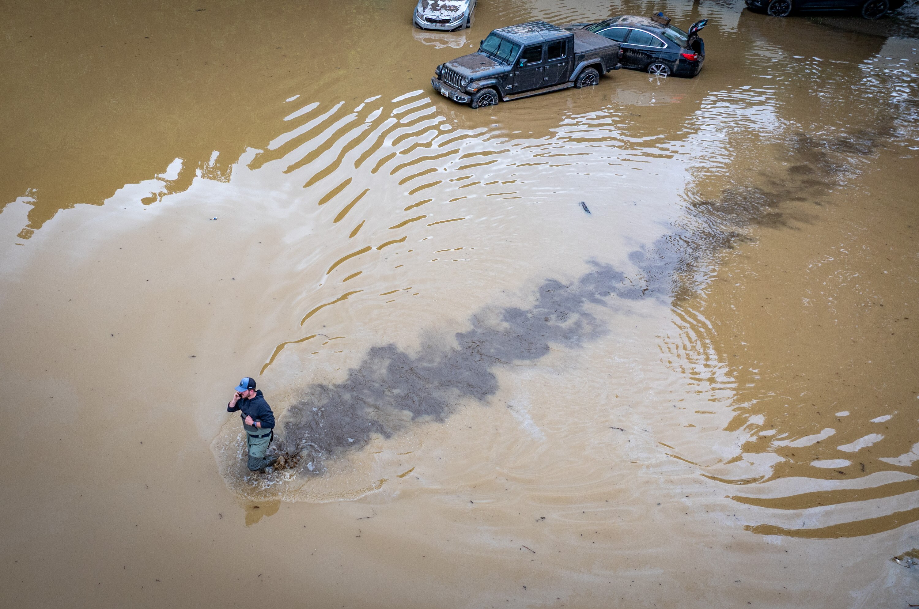 Aaron Fitzgerald wades through the flooded parking lot of Westernport Elementary School to retrieve belongings from his mother waterlogged car after a catastrophic storm hit the area on Tuesday.