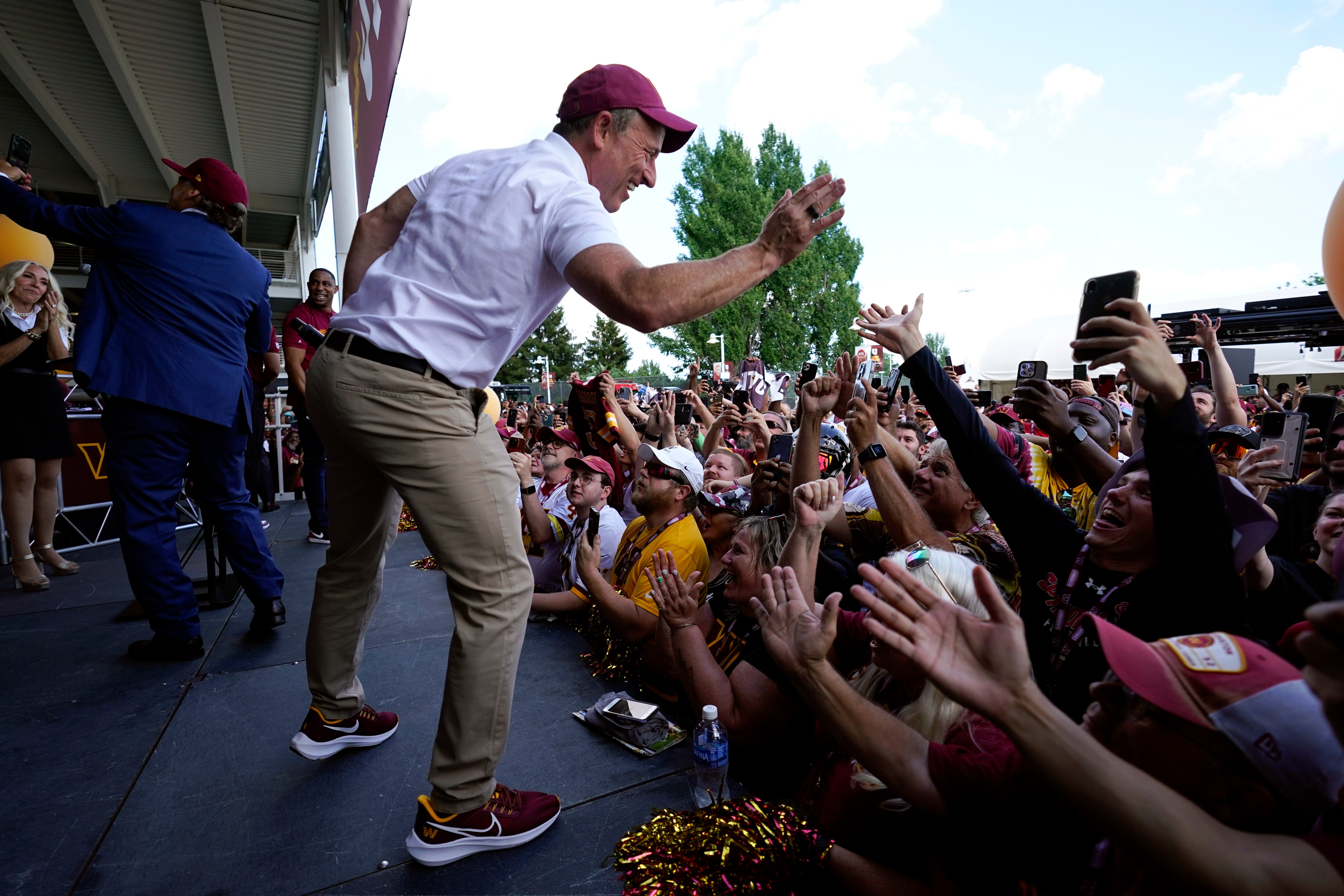 Josh Harris, the leader of a group buying the Washington Commanders, high-fives fans during a pep rally at FedEx Field on Friday. The new ownership's honeymoon period could be lengthened by the fans' relief at the departure of owner Dan Snyder.
