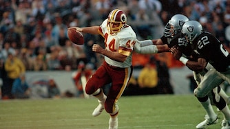 Washington Redskins running back John Riggins is pursued by Los Angeles Raiders defenders as he carries the ball during the Super Bowl XVIII in 1984.
