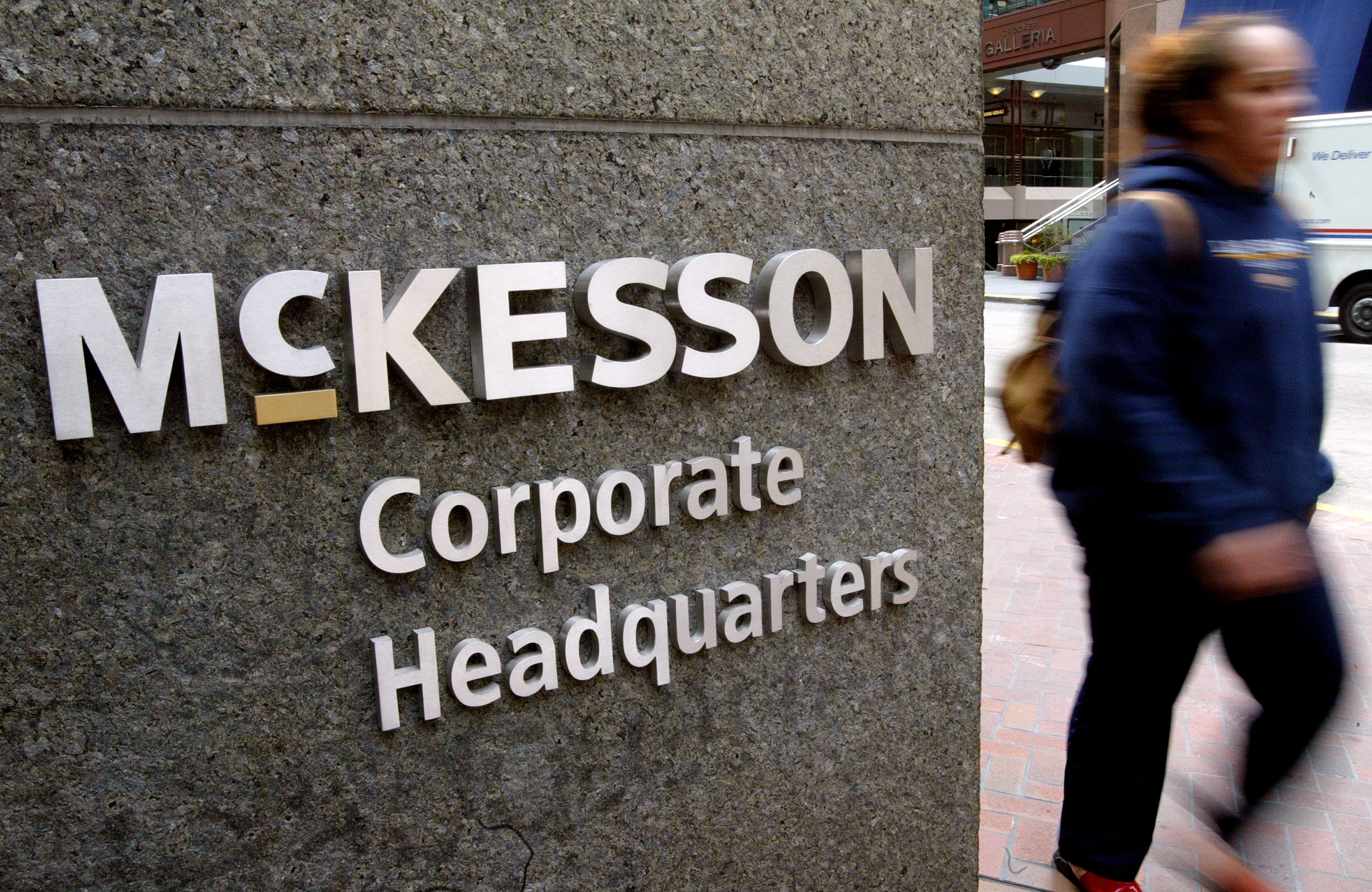 Metal letters on a stone wall spell McKesson Corporate Headquarters as a person walks by in the background
