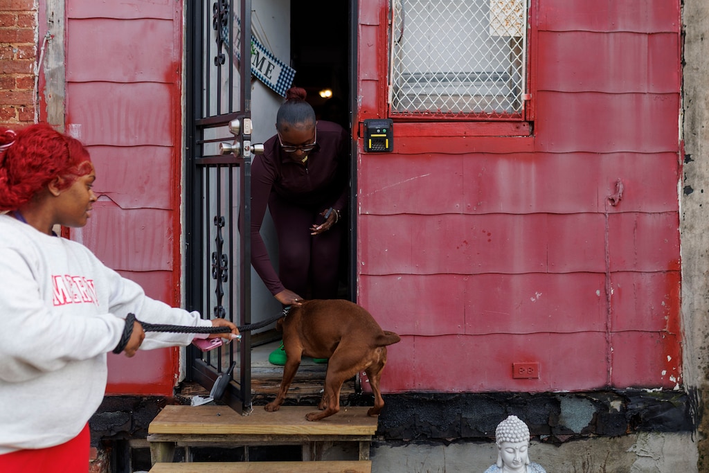Aajah Harris pets her sister Cairos dog outside of their family home. The Harris’ family home of generations was sold in a tax sale without the family’s knowledge.