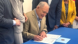 Montgomery County Executive Marc Elrich signs an executive order Friday issuing a six-month moratorium on data center permits, while flanked by supporters. The temporary ban is Elrich’s answer to months of debate on the issue.