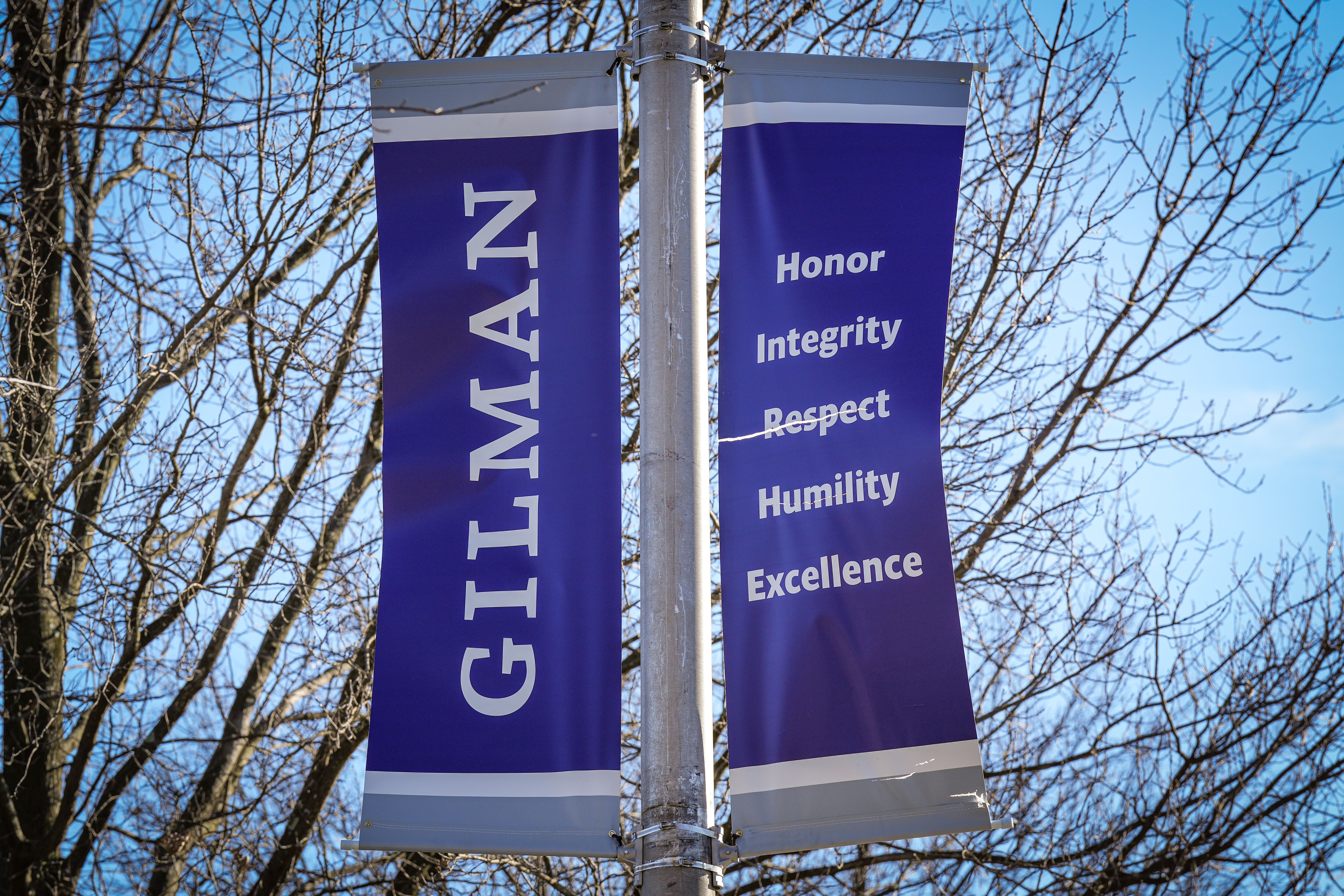 A lamppost outside the Gilman School holds banner's with the institution's name and values on them on March 16, 2023.