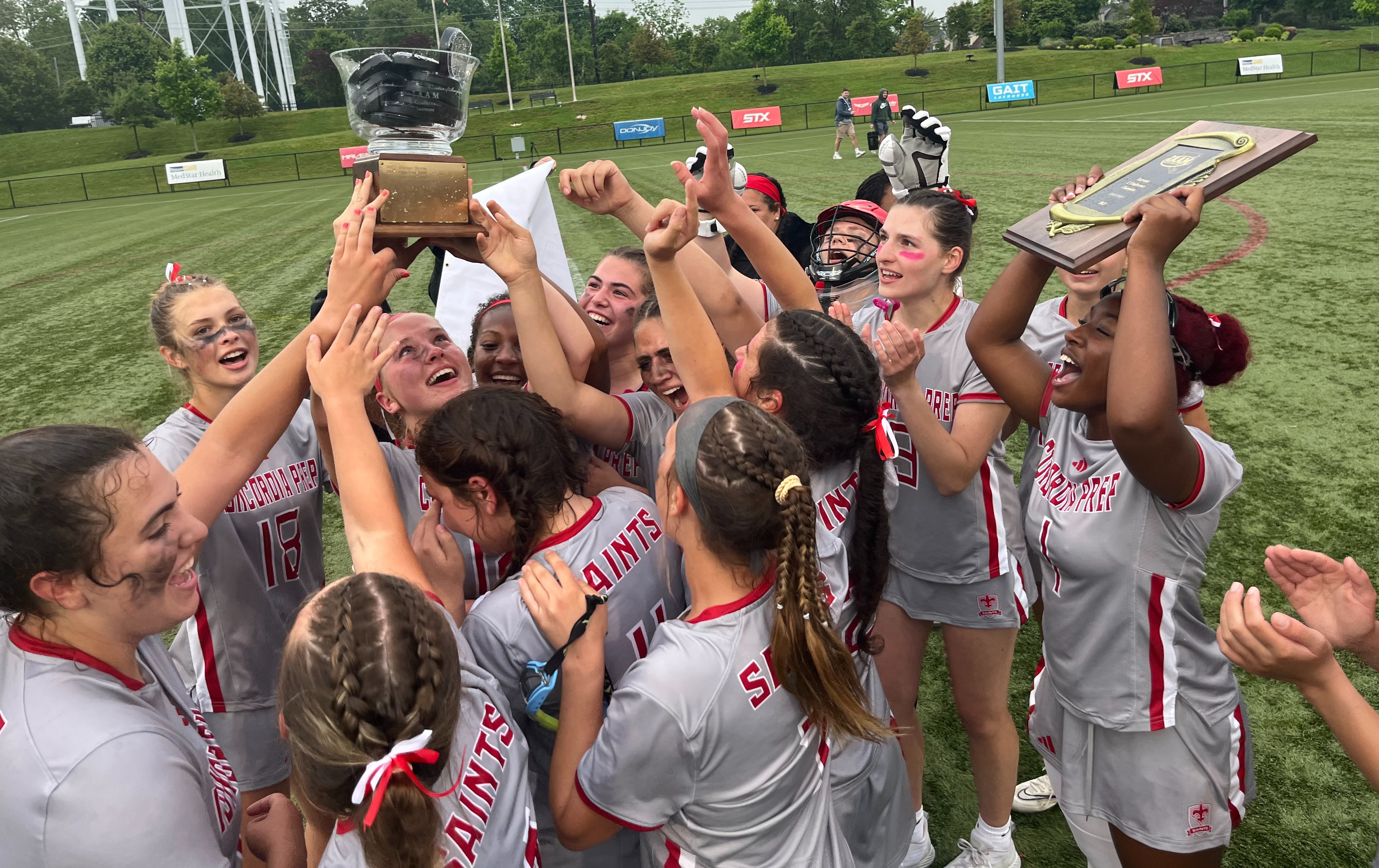 Concordia Prep lacrosse team celebrates after receiving the IAAM C Conference championship trophy and plaque. The Saints, who won two games in 2022, capped a perfect season (13-0) with a 17-10 victory over Catholic at USA Lacrosse's Tierney Field in Sparks.