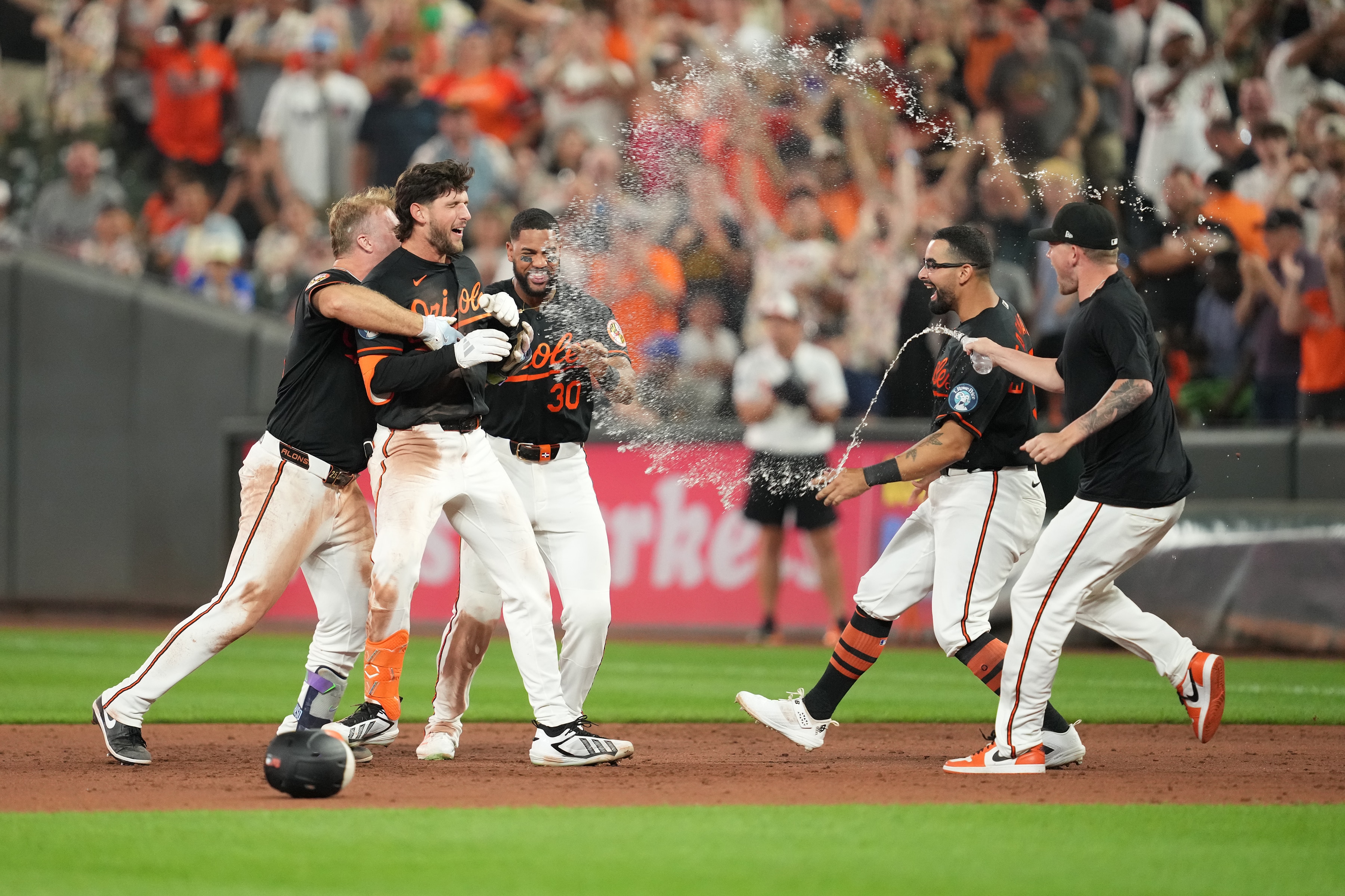 Orioles teammates surround Dylan Beavers after his walk-off single Saturday night against the Braves.