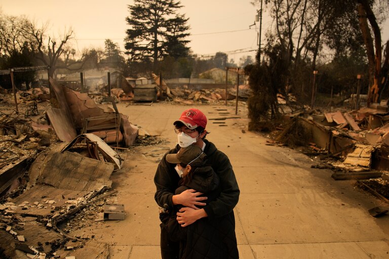 Ari Rivera, rear, Anderson Hao hold each other in front of their destroyed home in Altadena, Calif., Thursday, Jan. 9, 2025.