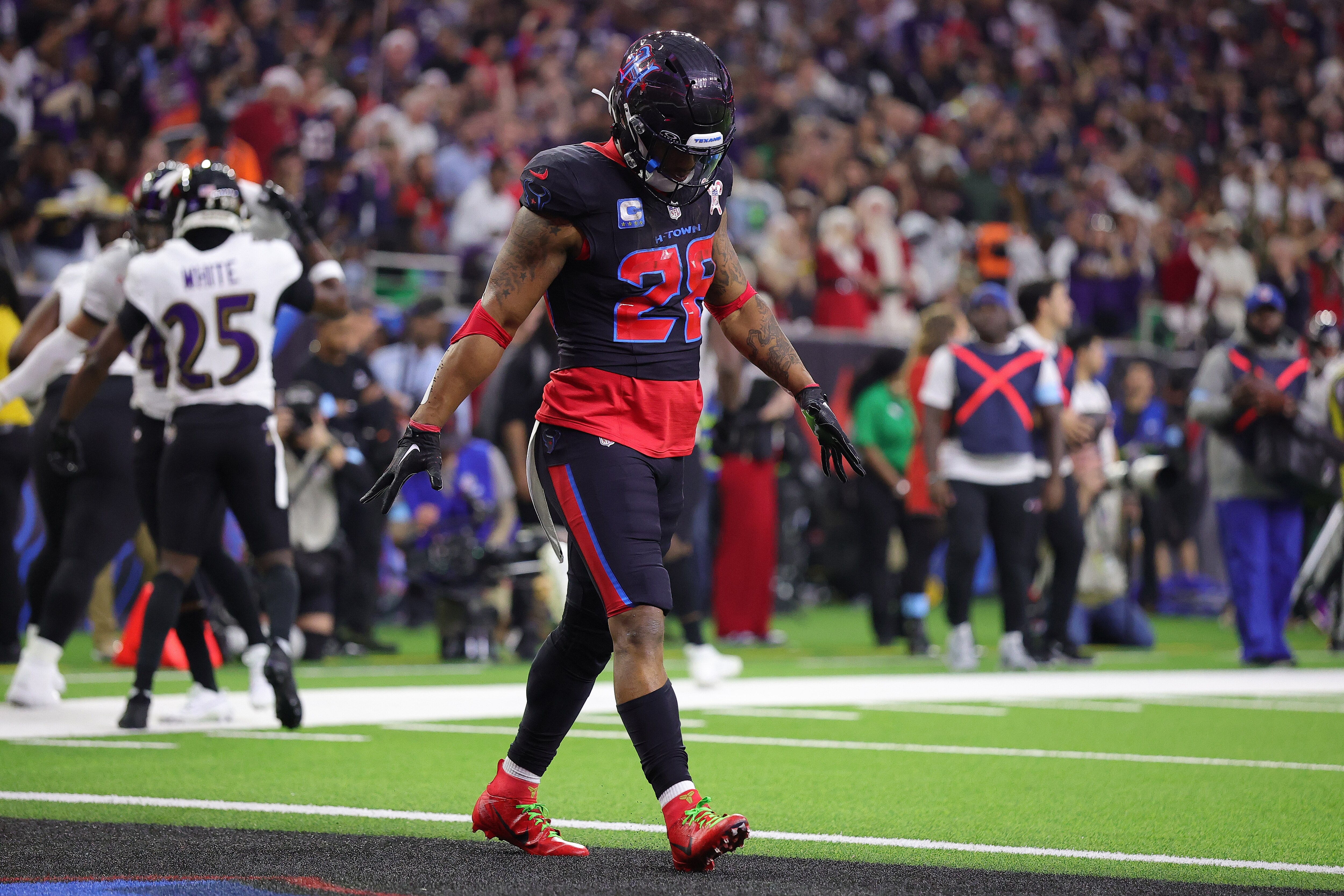 The Ravens celebrate a goal-line stand as the Texans’ Joe Mixon walks off Saturday during the second quarter.