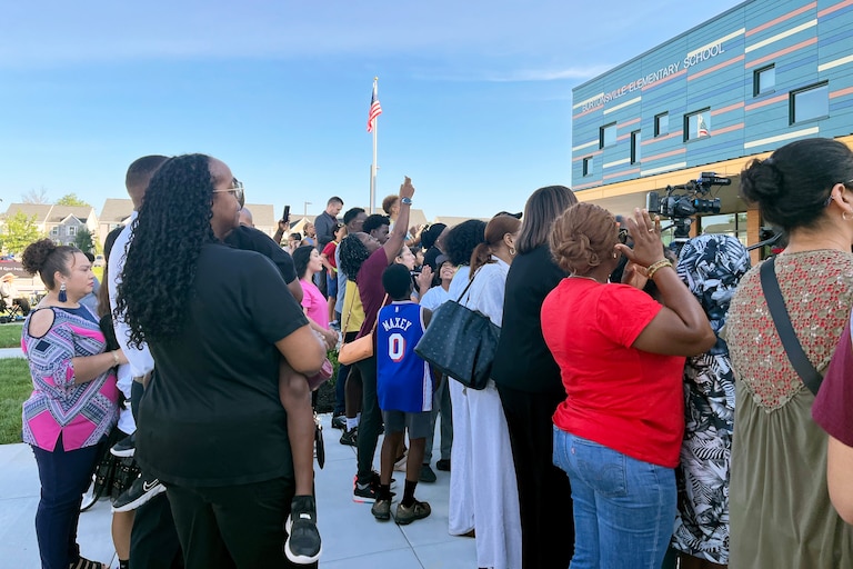 Nicole Stennett holds her 6-year-old son Nicholas so he can watch the ribbon-cutting ceremony at his new elementary school.
