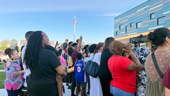 Nicole Stennett holds her 6-year-old son Nicholas so he can watch the ribbon-cutting ceremony at his new elementary school.