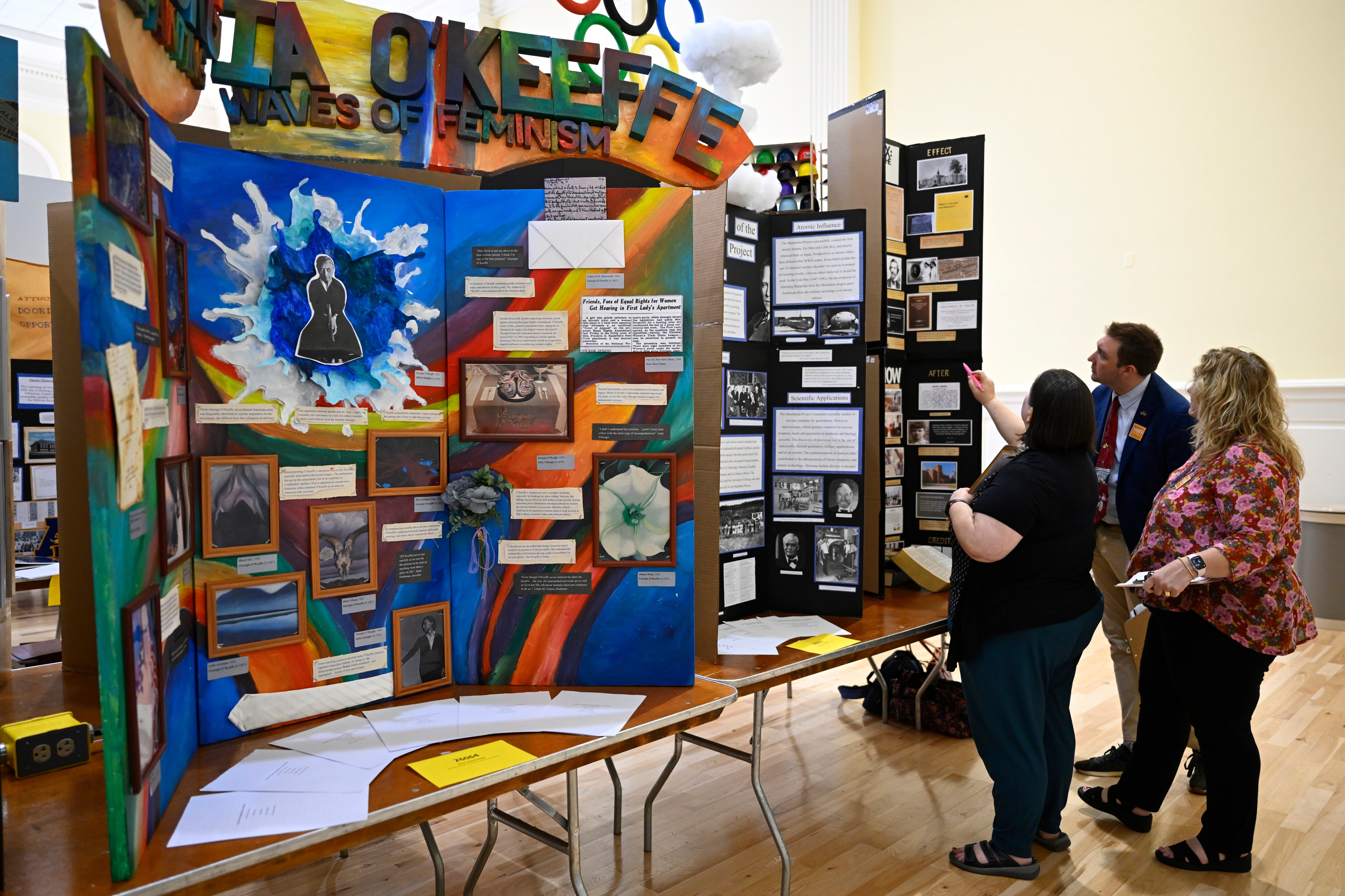 Judges Stefanie Mathew (left), Cody Ingraham and Patrice Richter (right) examine one of the many historical exhibits by high school students on display at the National History Day event at the University of Maryland.