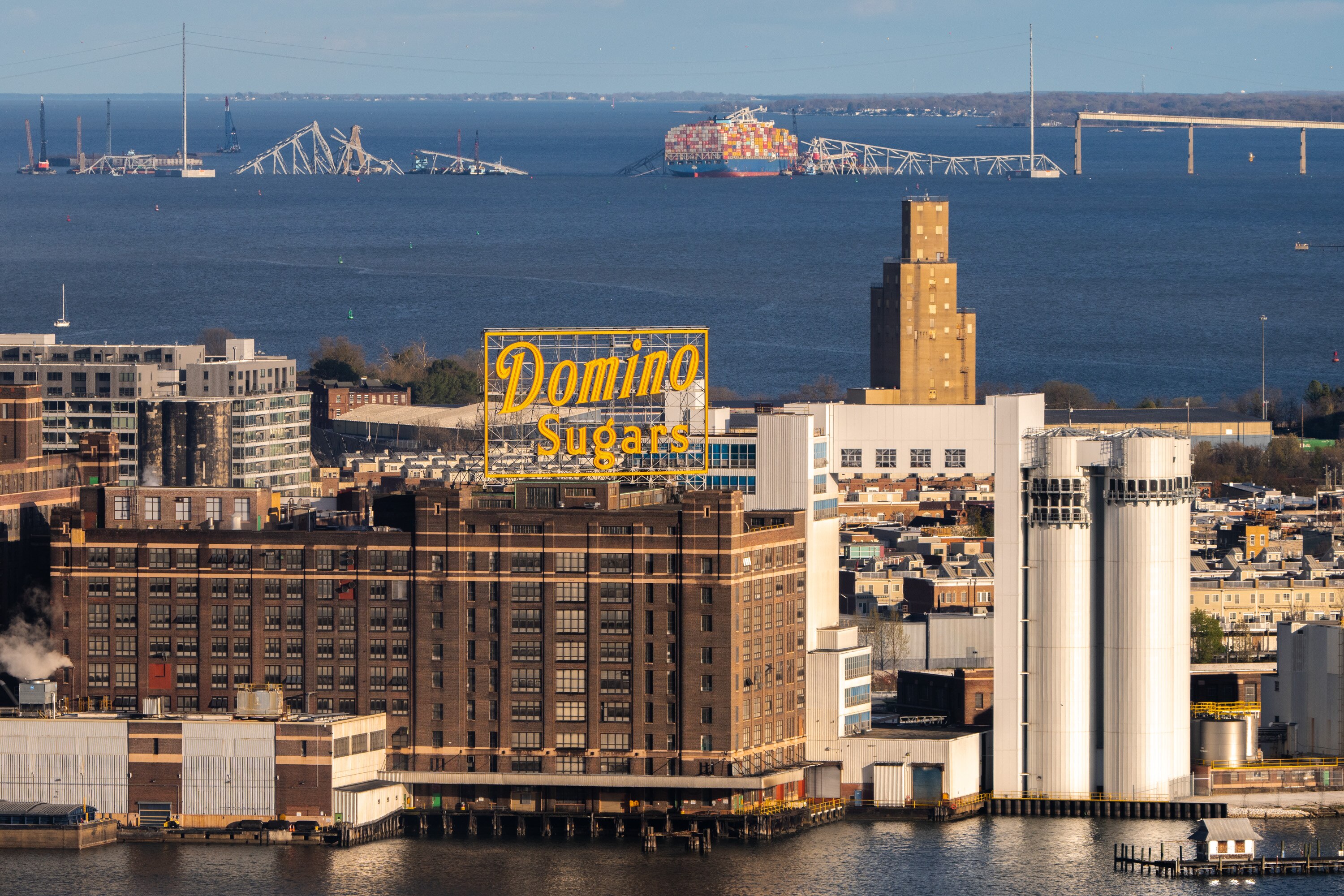 The wreckage of the Key Bridge collapse, with the Domino Sugar factory in the foreground, is seen from the Baltimore World Trade Center on April 6.