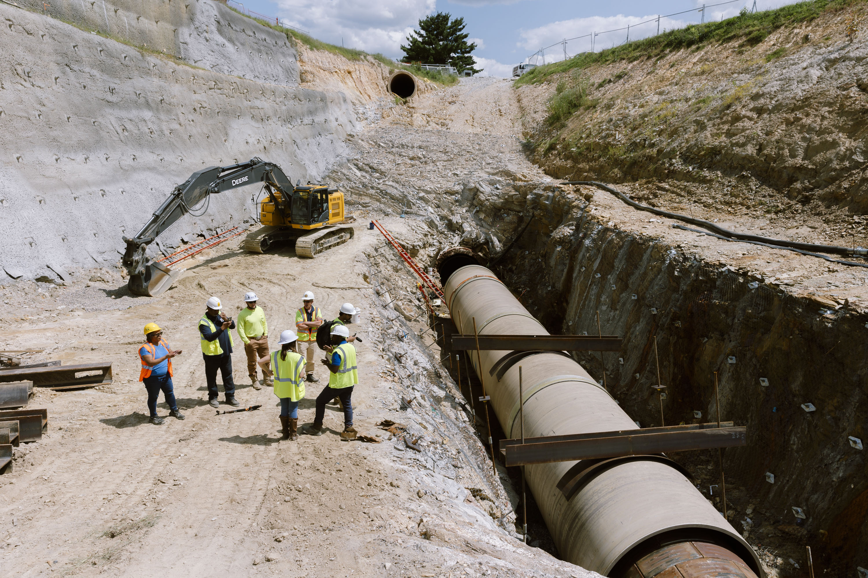 The new steel and cement replacement pipe can be seen next to a group of representatives from DPW, Garney Construction and The Baltimore Banner at the bottom of a six-story deep excavation at Lake Montebello on Thursday, Aug. 22, 2024 in Baltimore, MD.