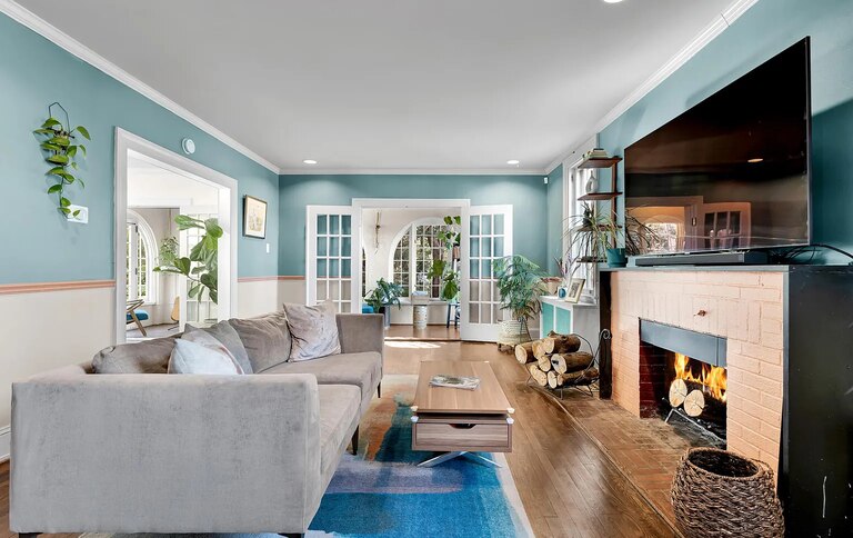 A living room with a wood-burning fireplace, modern furniture and bright blue walls.