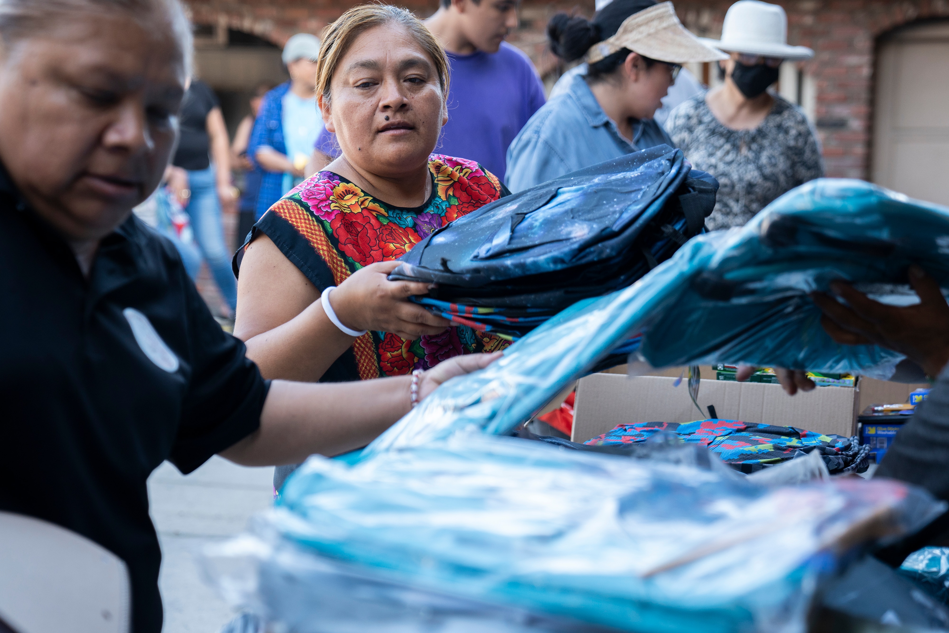 The lives of immigrant families have been roiled since President Donald Trump returned to office. Norma Gómez, with the Mixteco Indigena Community Organizing Project, distributes school supplies at an event supporting those who care for children with one or both parents in immigration detention.