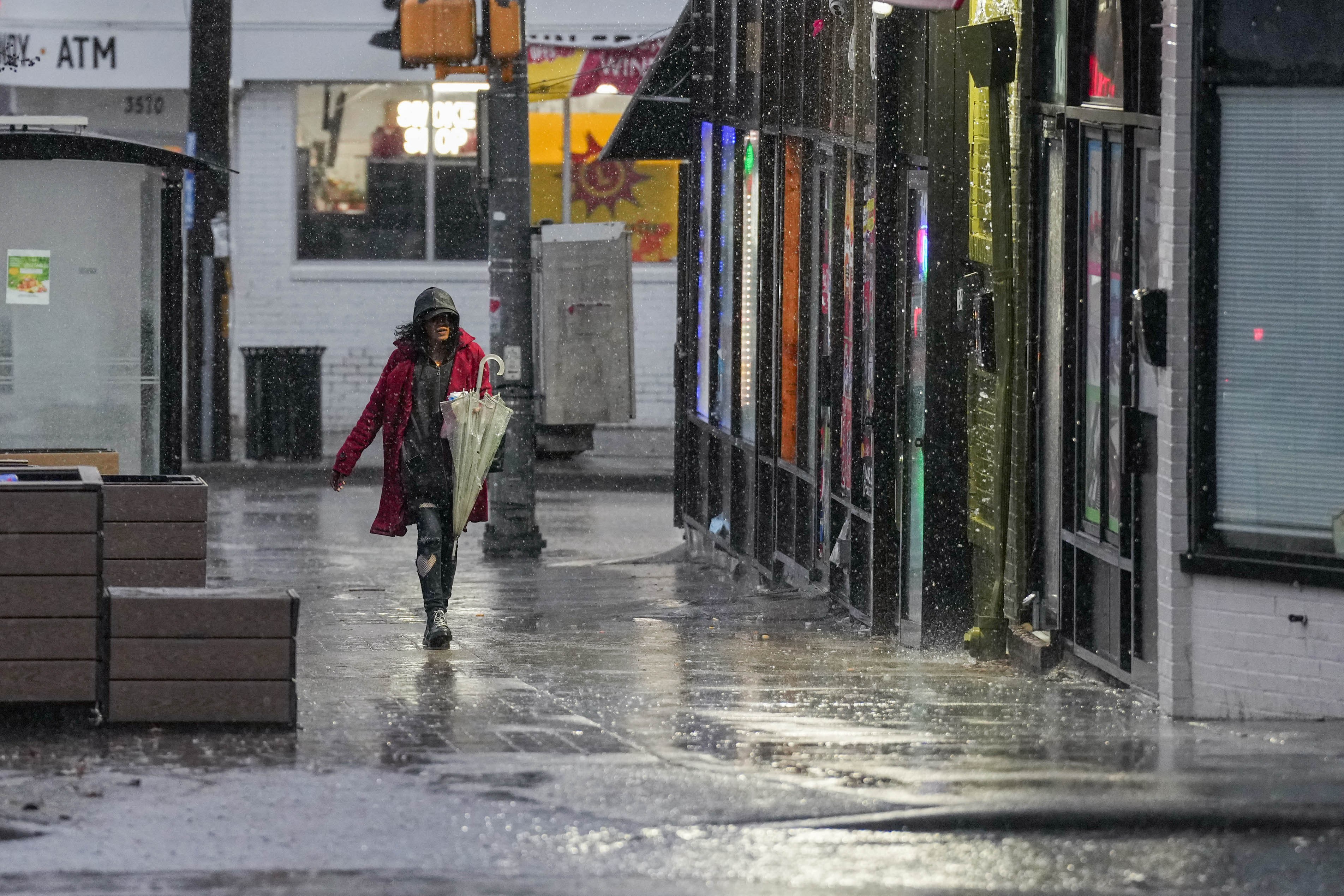A woman with an umbrella walks past shops on E. Patapsco Ave. on a rainy day in Brooklyn, Md. on Wednesday, March 5, 2025.