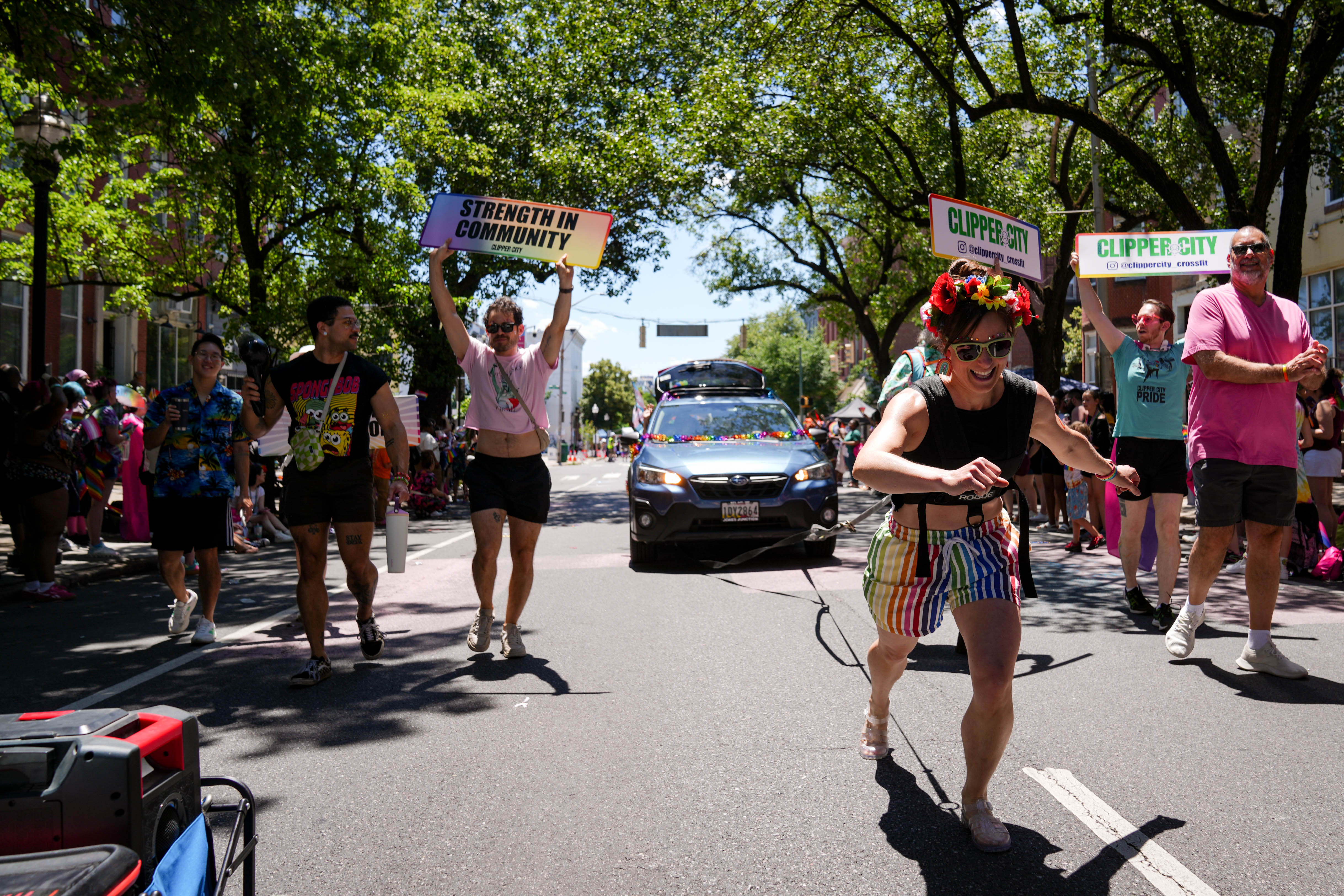 Members of Clipper City Crossfit take turns pulling a car forward in the Baltimore Pride parade Saturday.