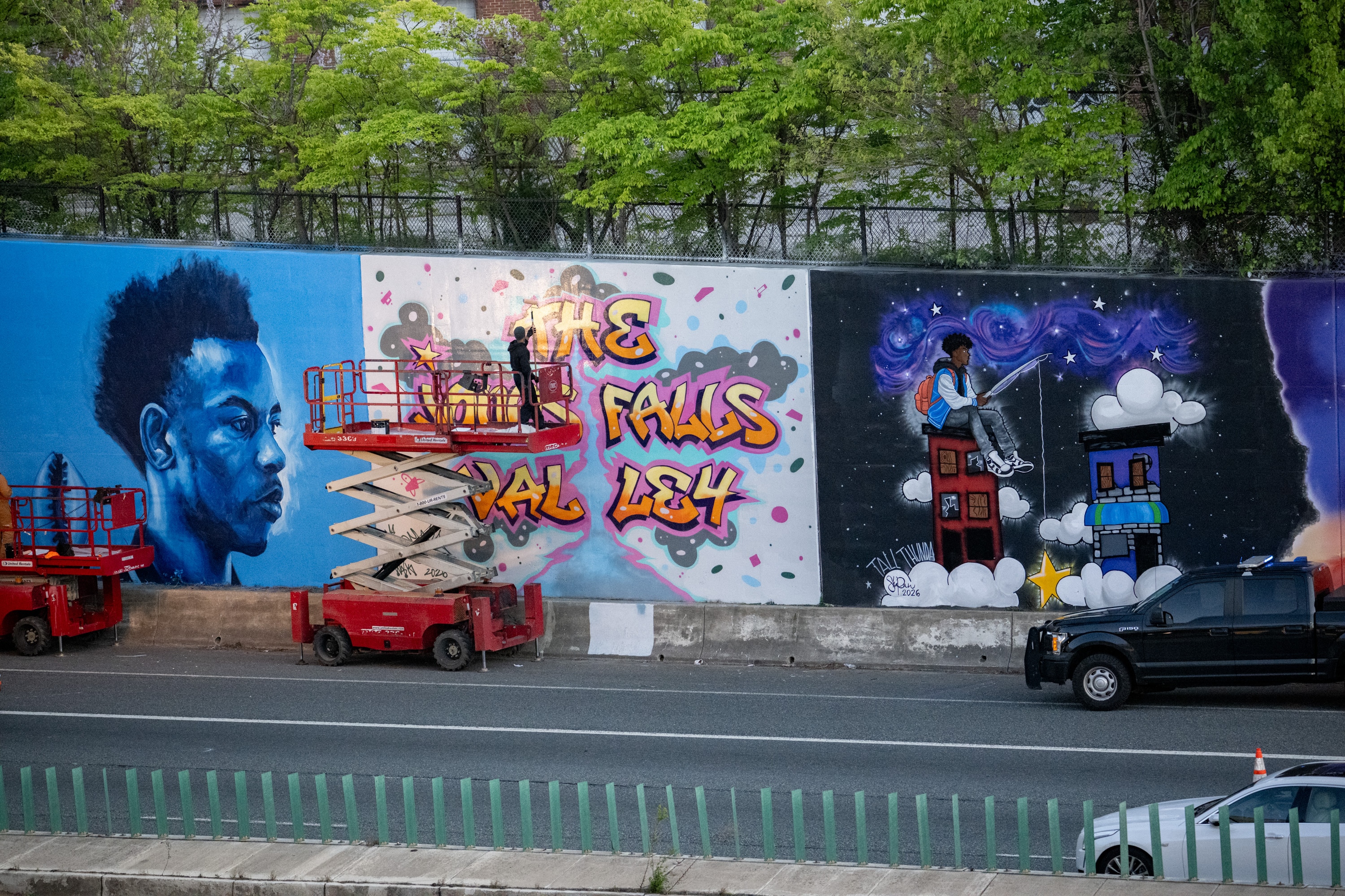 RodSzn, assistant coordinator for local artist D Star, stands on a lift as he works on a new mural by D Star along the southbound Jones Falls Expressway earlier this week as part of the “Art After Dark” initiative.